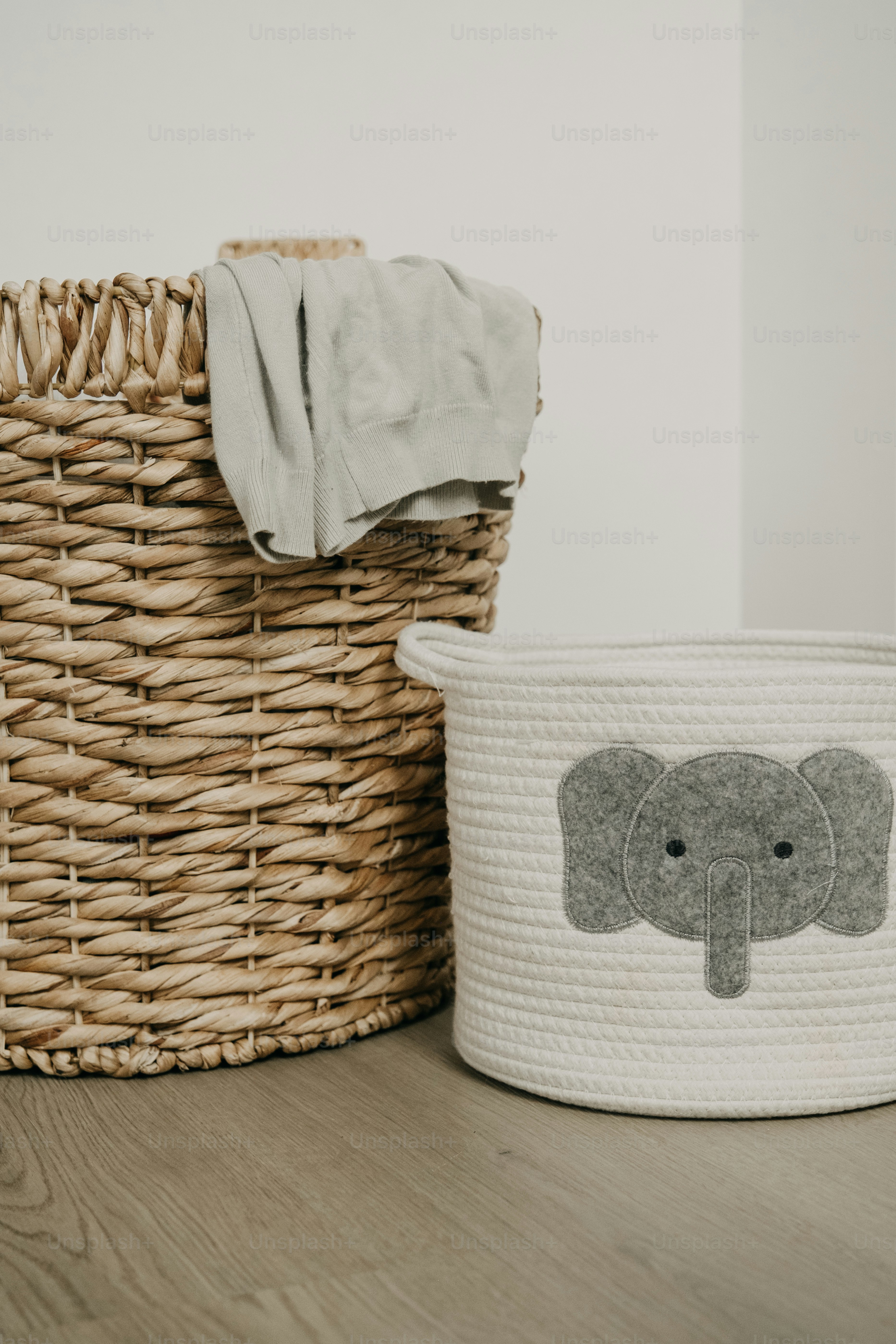 Two storage baskets, one with an elephant design.