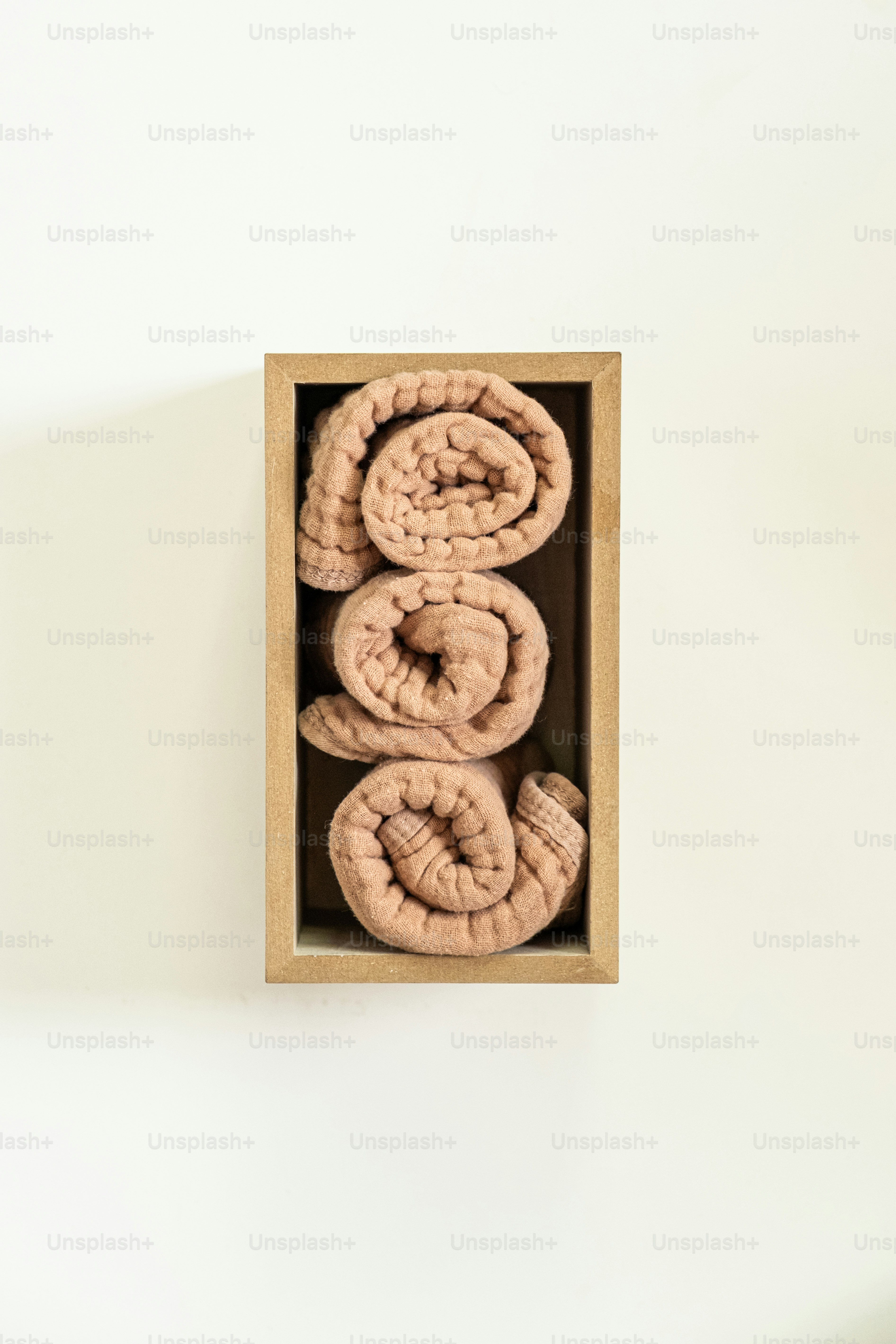 Three rolled blankets neatly arranged in a wooden box.