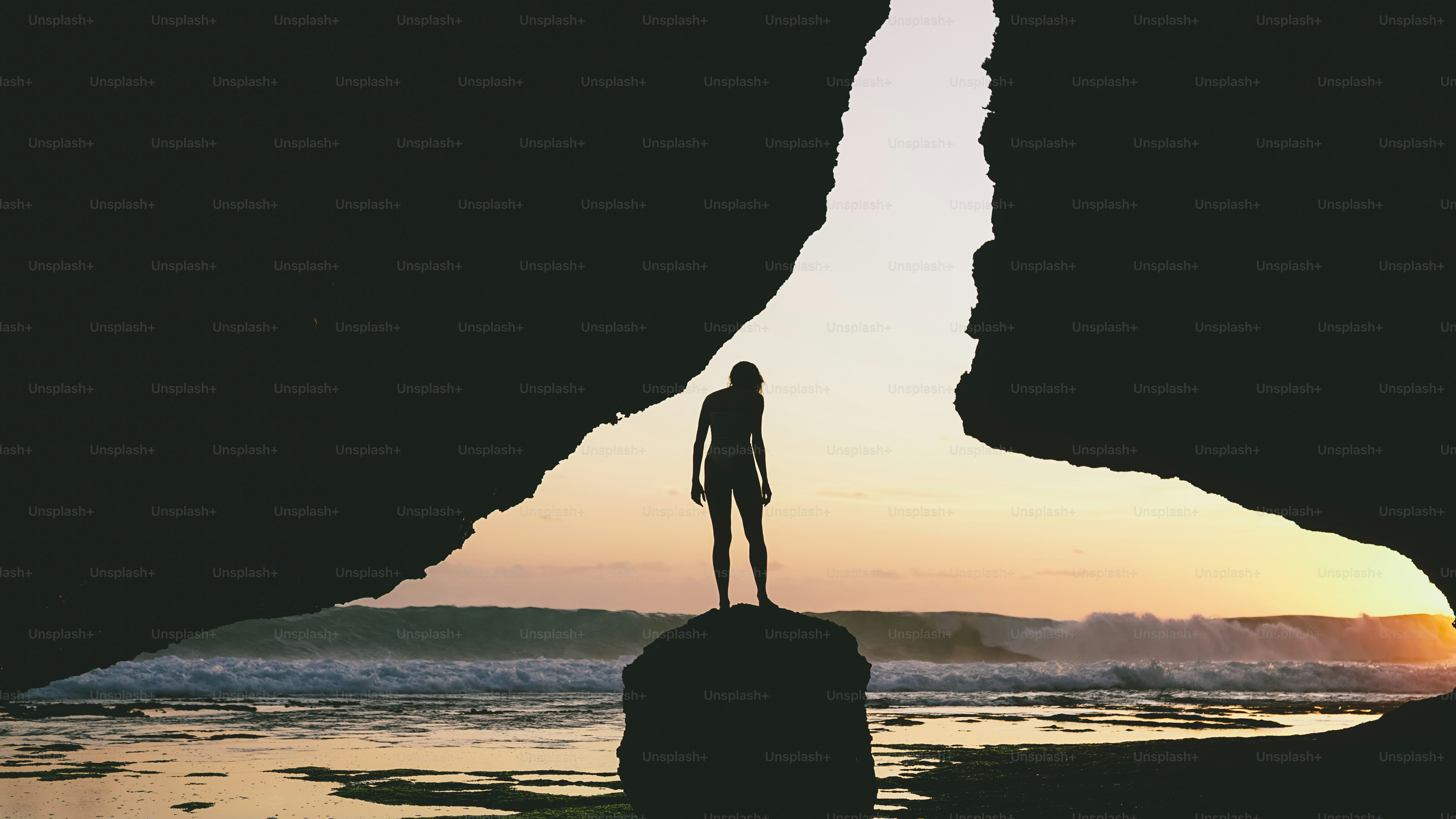 Silhouette di una persona in piedi su una roccia al tramonto