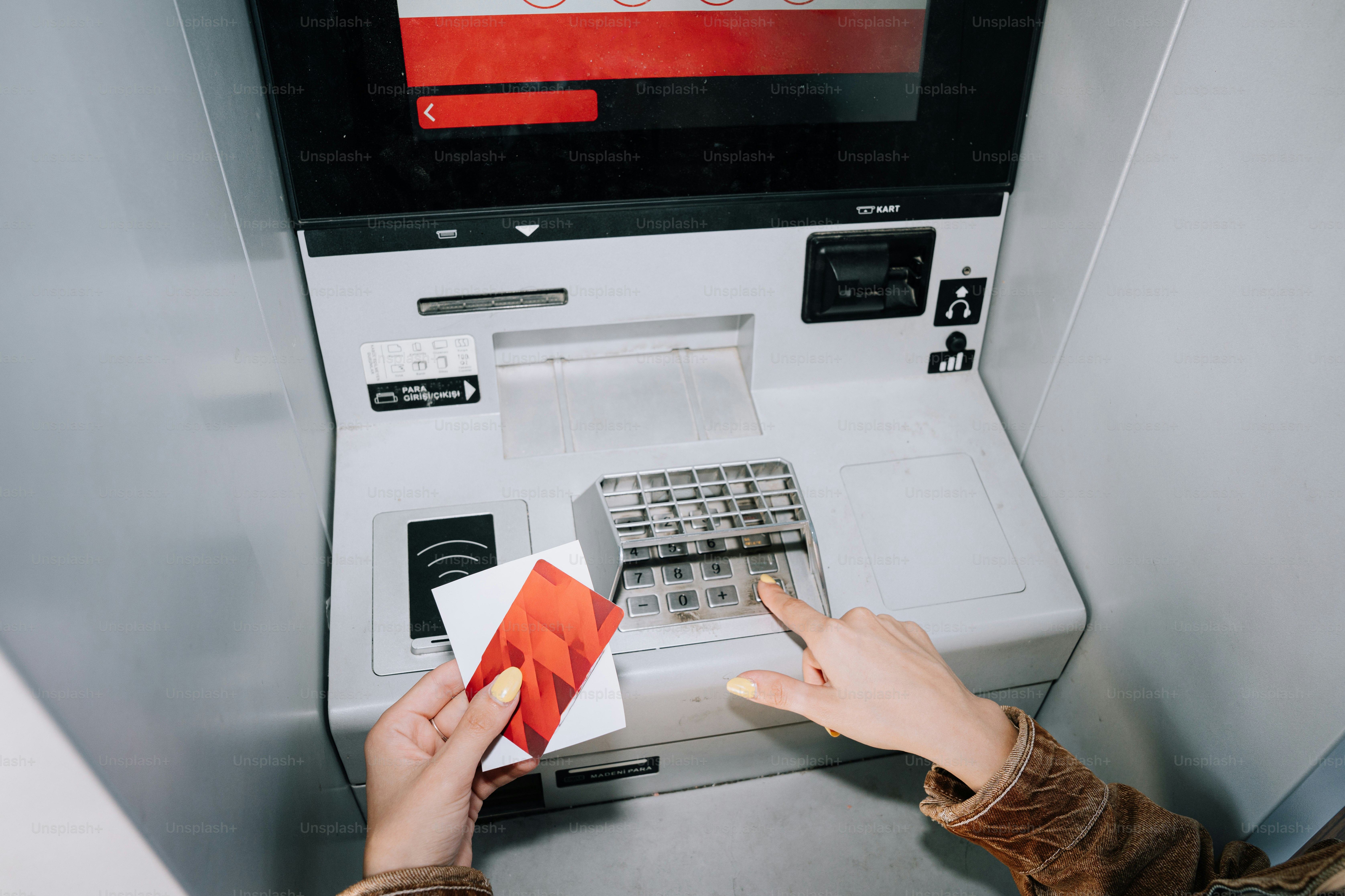 Person using atm with credit card and keypad.