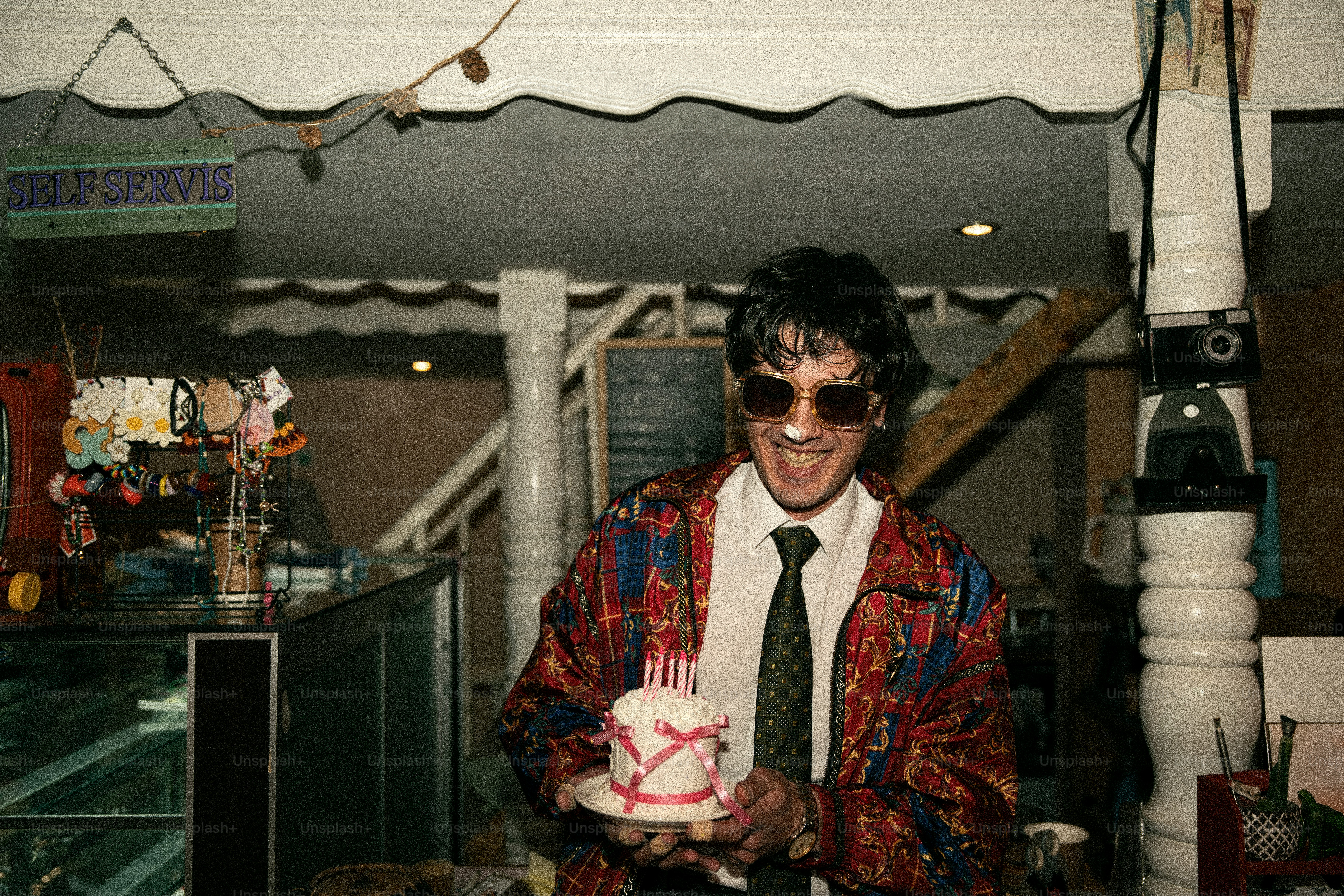 Man in sunglasses holds a small birthday cake with candles.