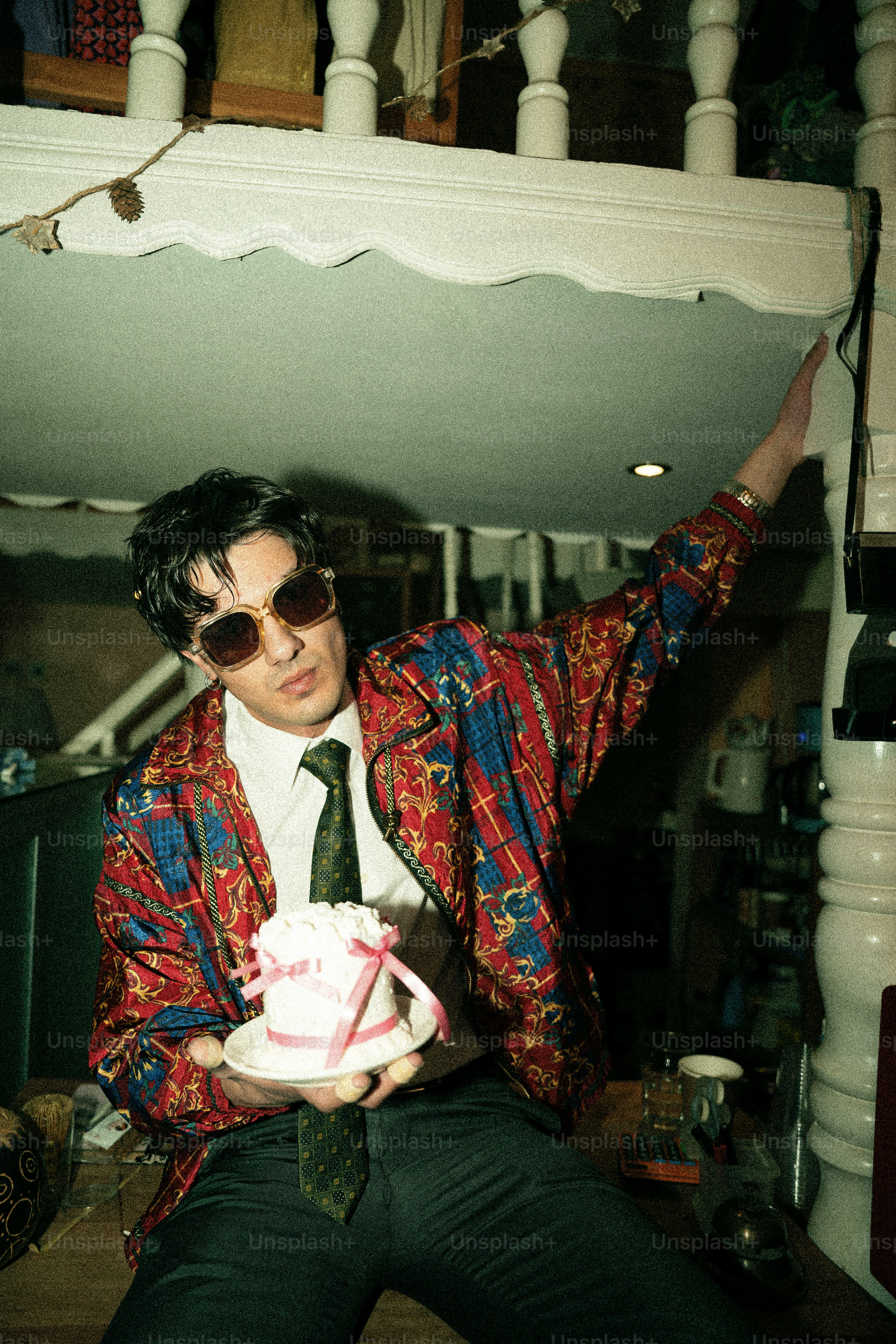 Man in colorful jacket holds small cake
