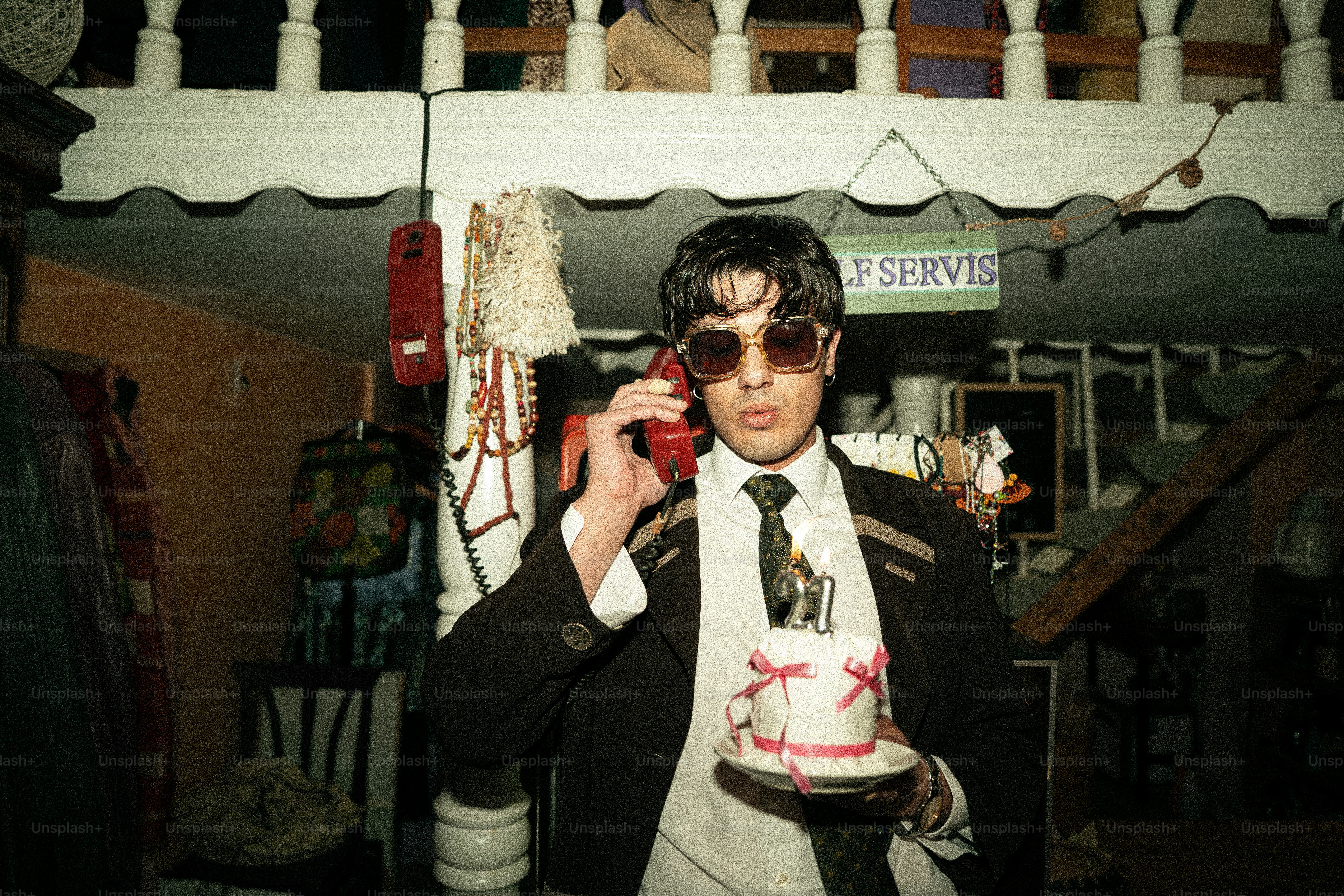 Man in suit holding phone and small cake