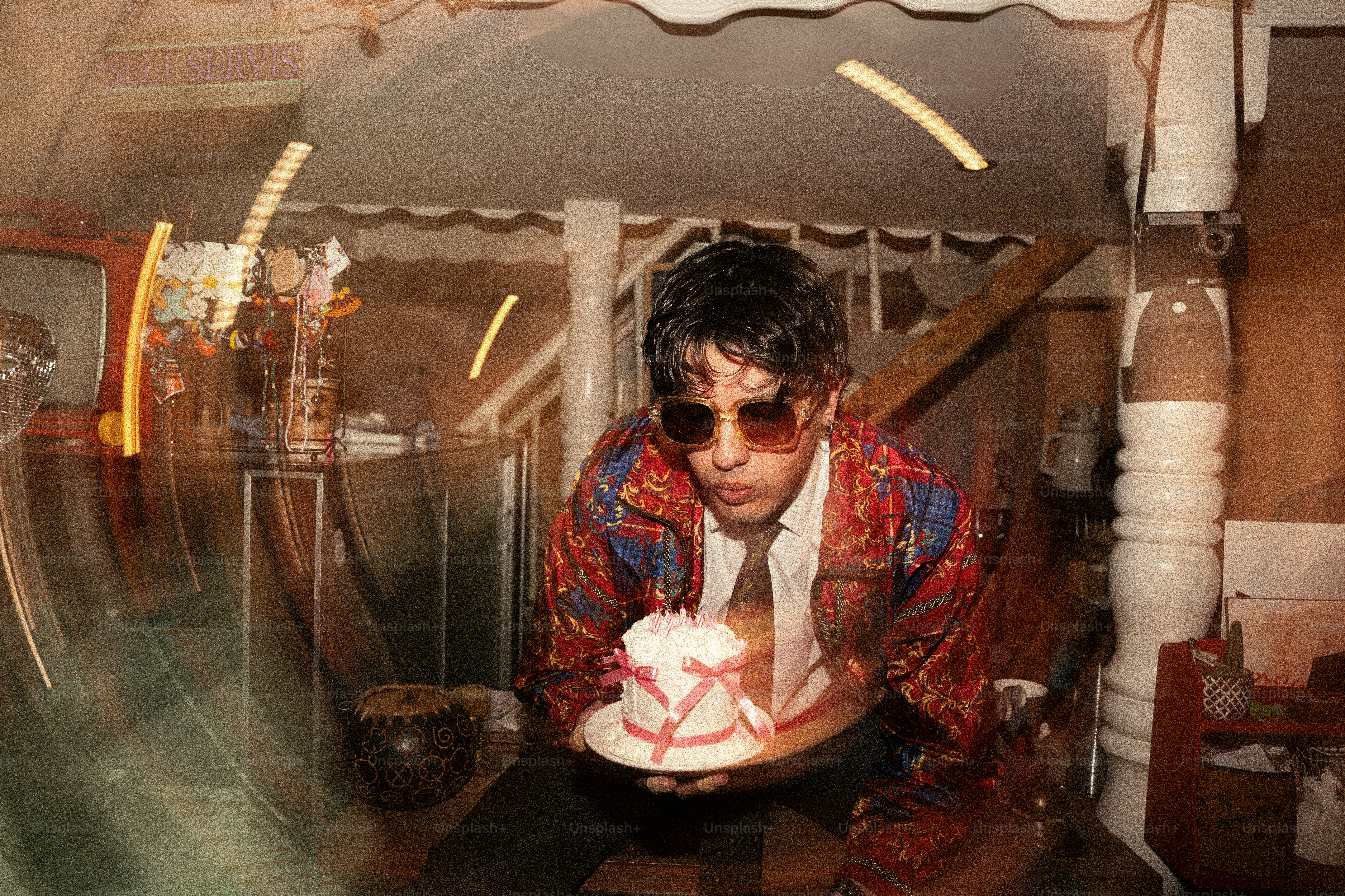 Man in sunglasses blows out birthday cake candles