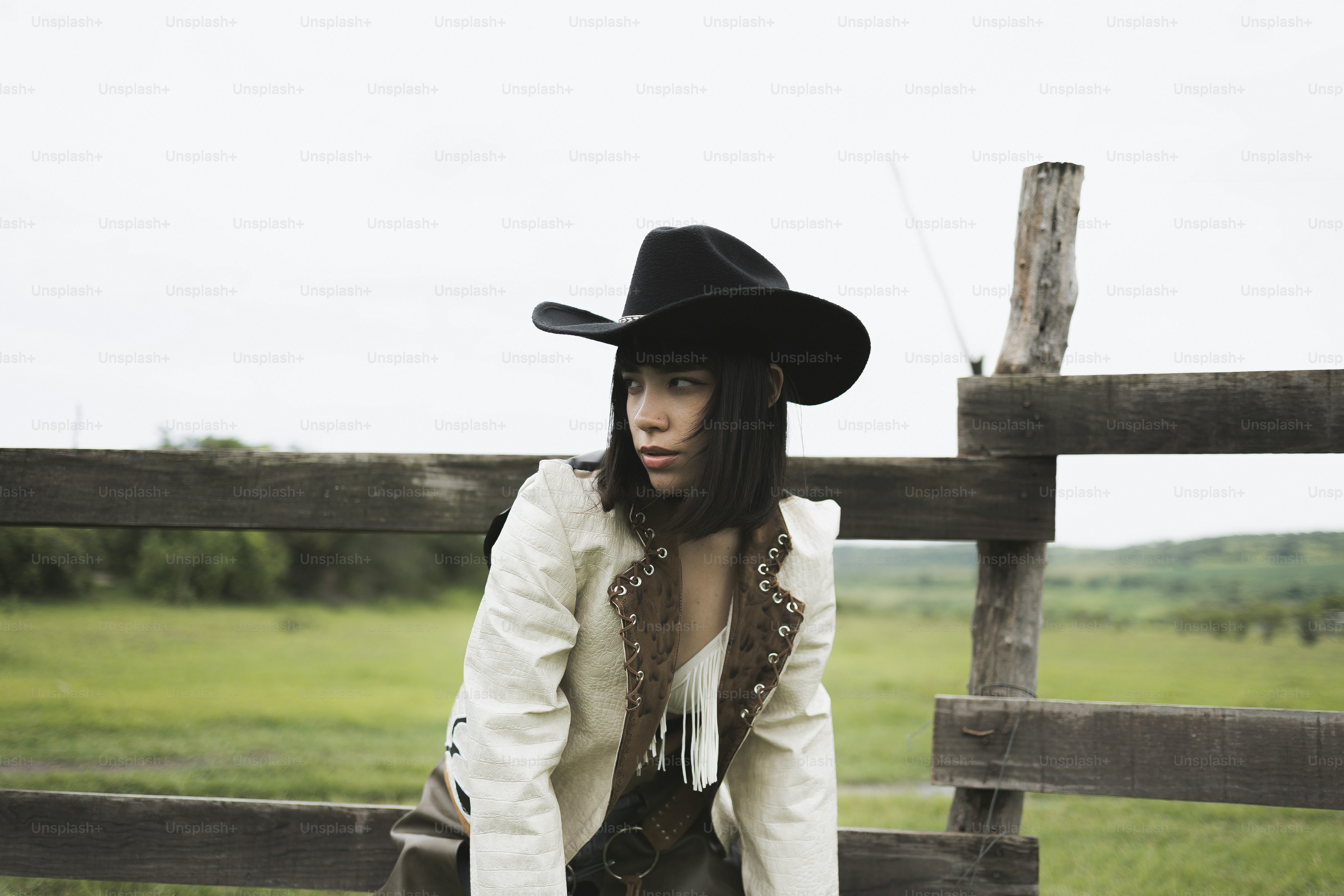 Femme en chapeau de cow-boy et veste sur la clôture du ranch