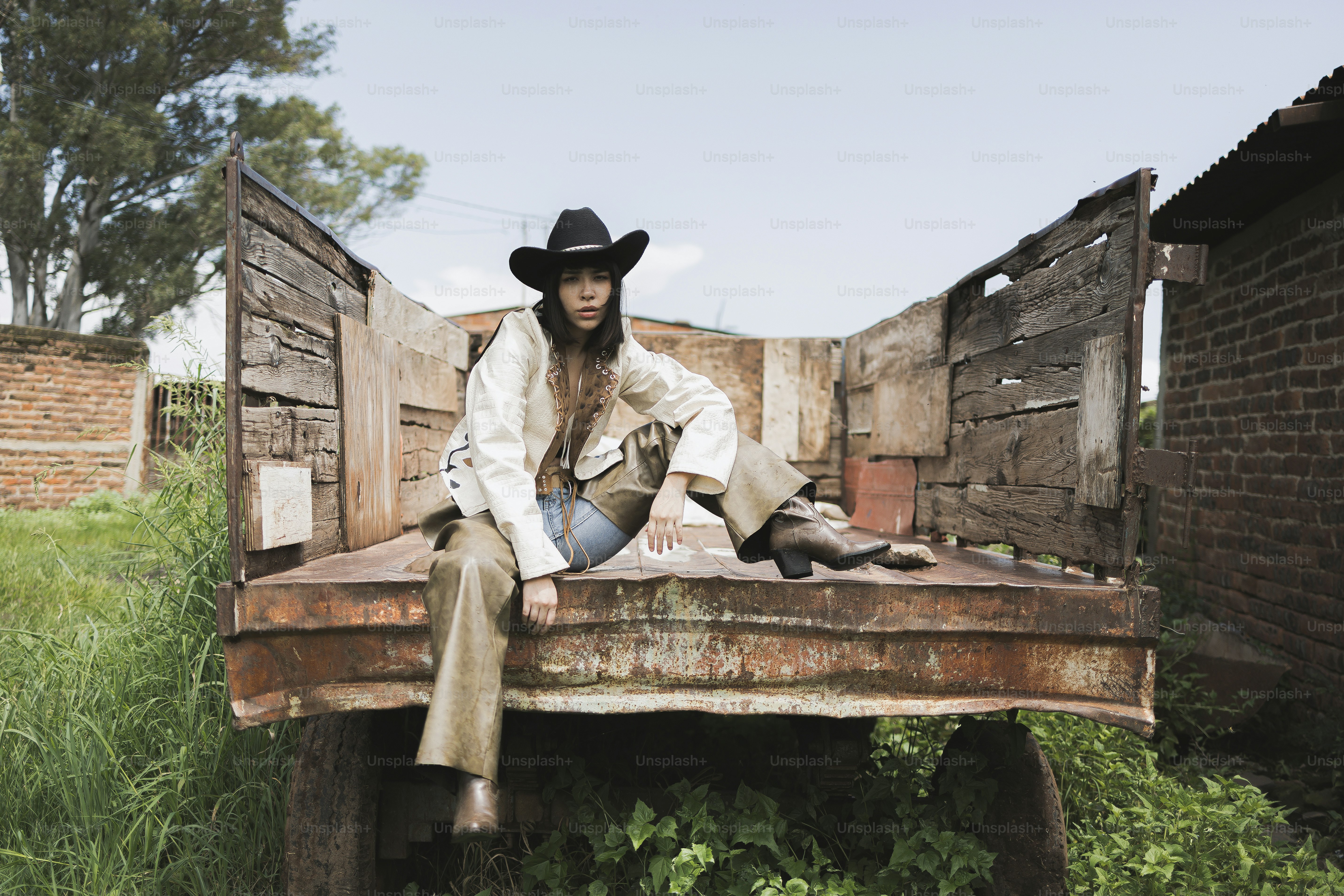 Woman in cowboy hat sits in old truck bed