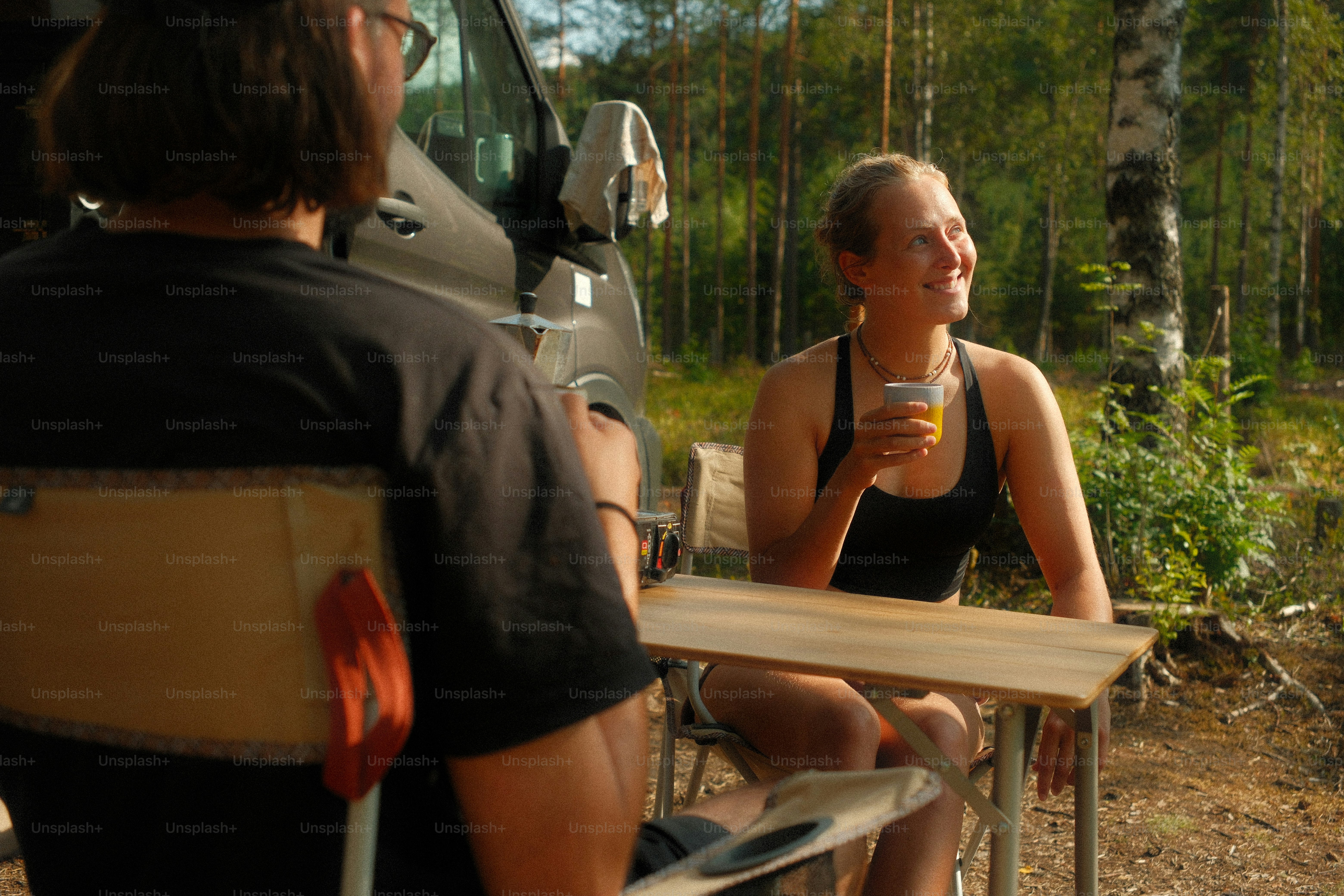 Paar genießt Getränke in einem Van im Wald