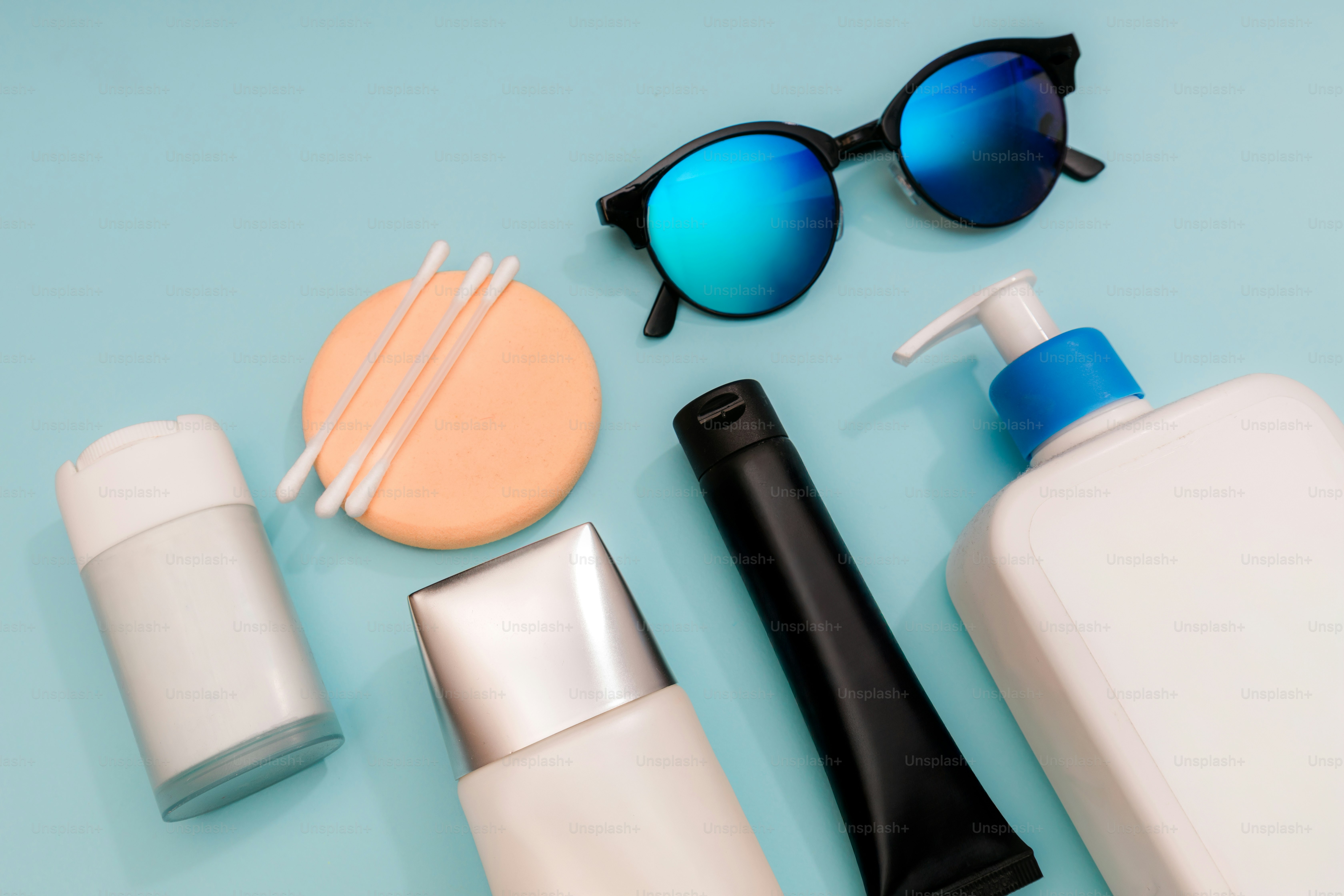 Various beauty products and sunglasses arranged on blue surface