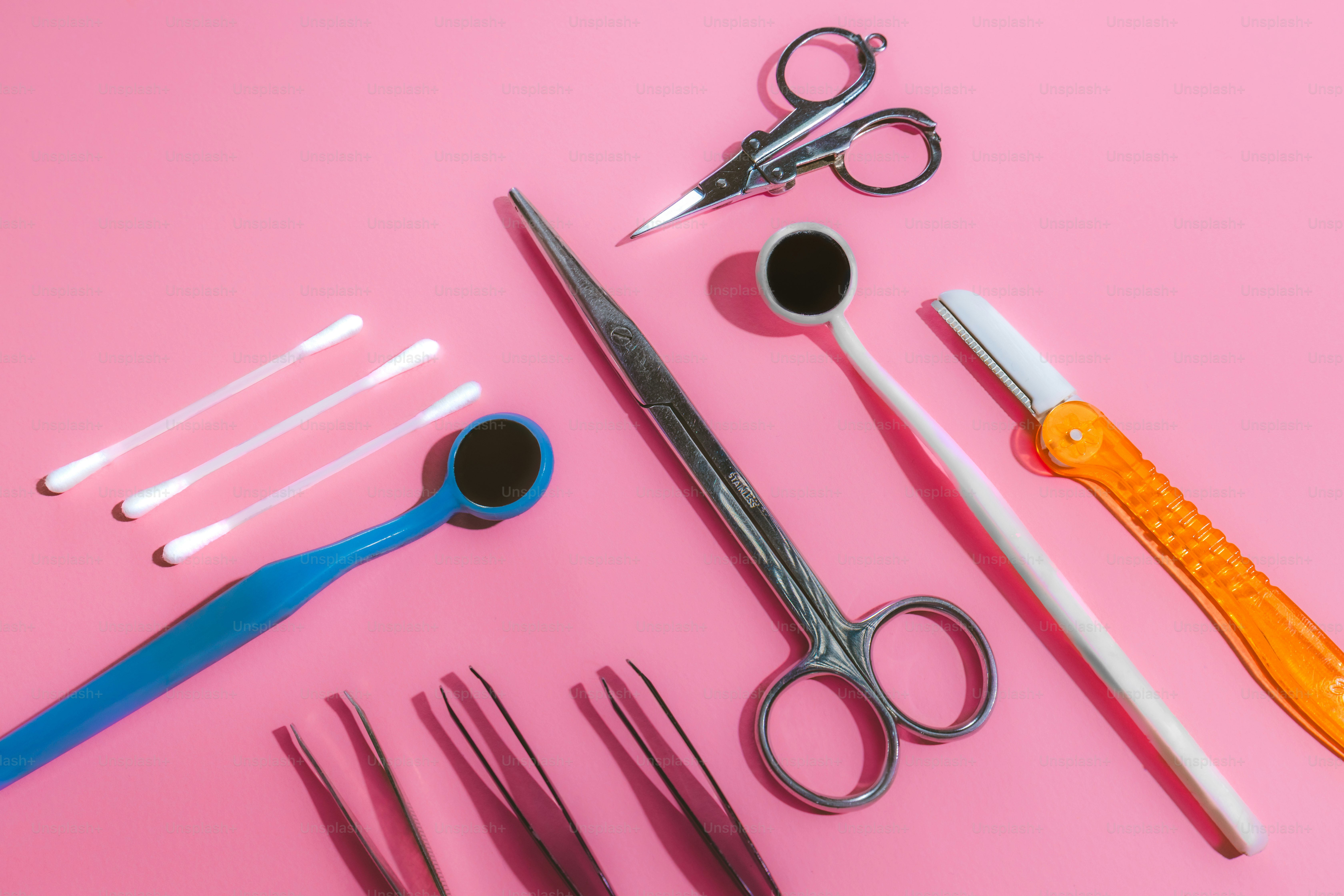 Dental tools and cotton swabs arranged on pink background