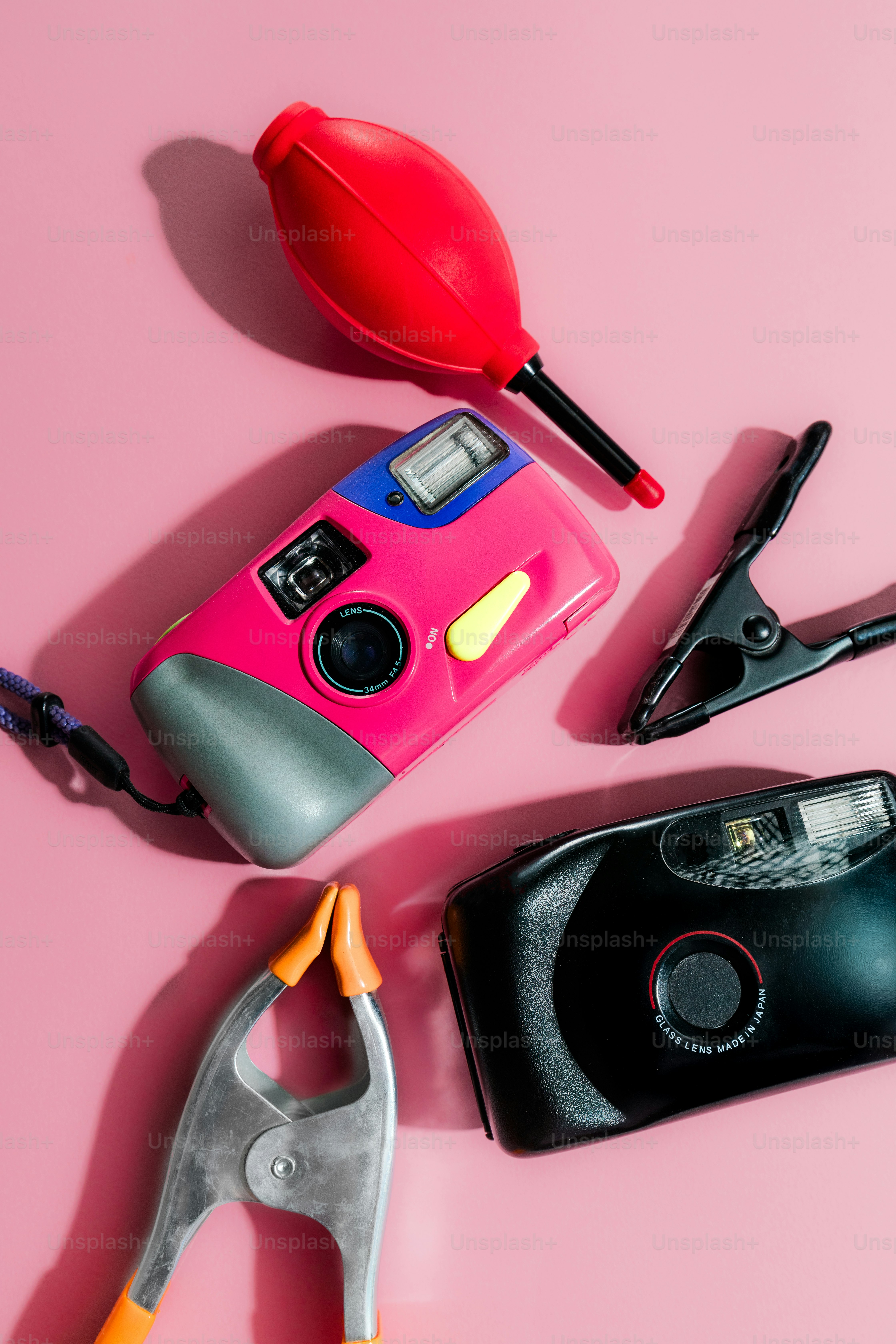 Two cameras, blower, and clamps on pink background