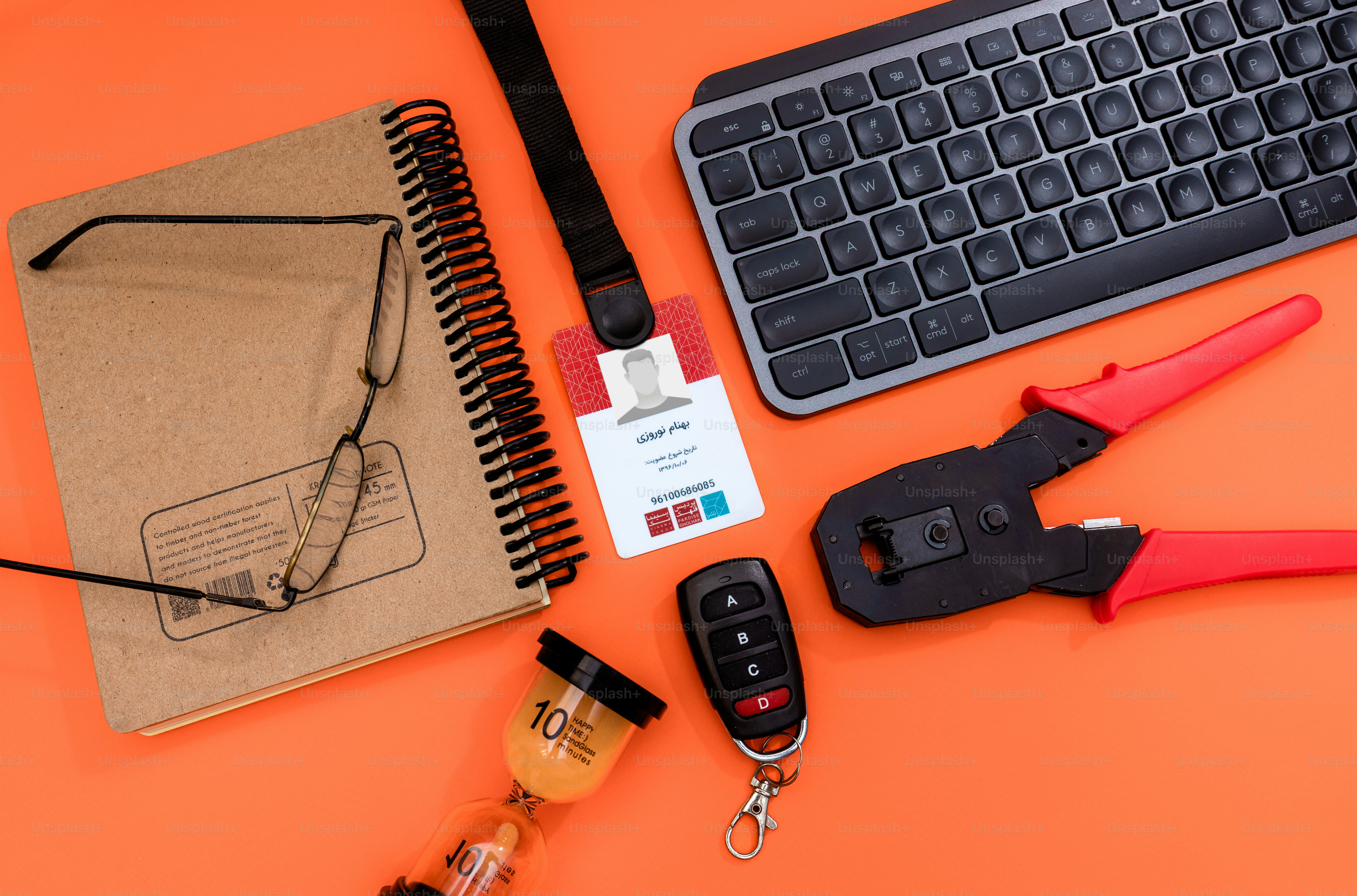 Desk items including keyboard, pliers, notebook, and car key.