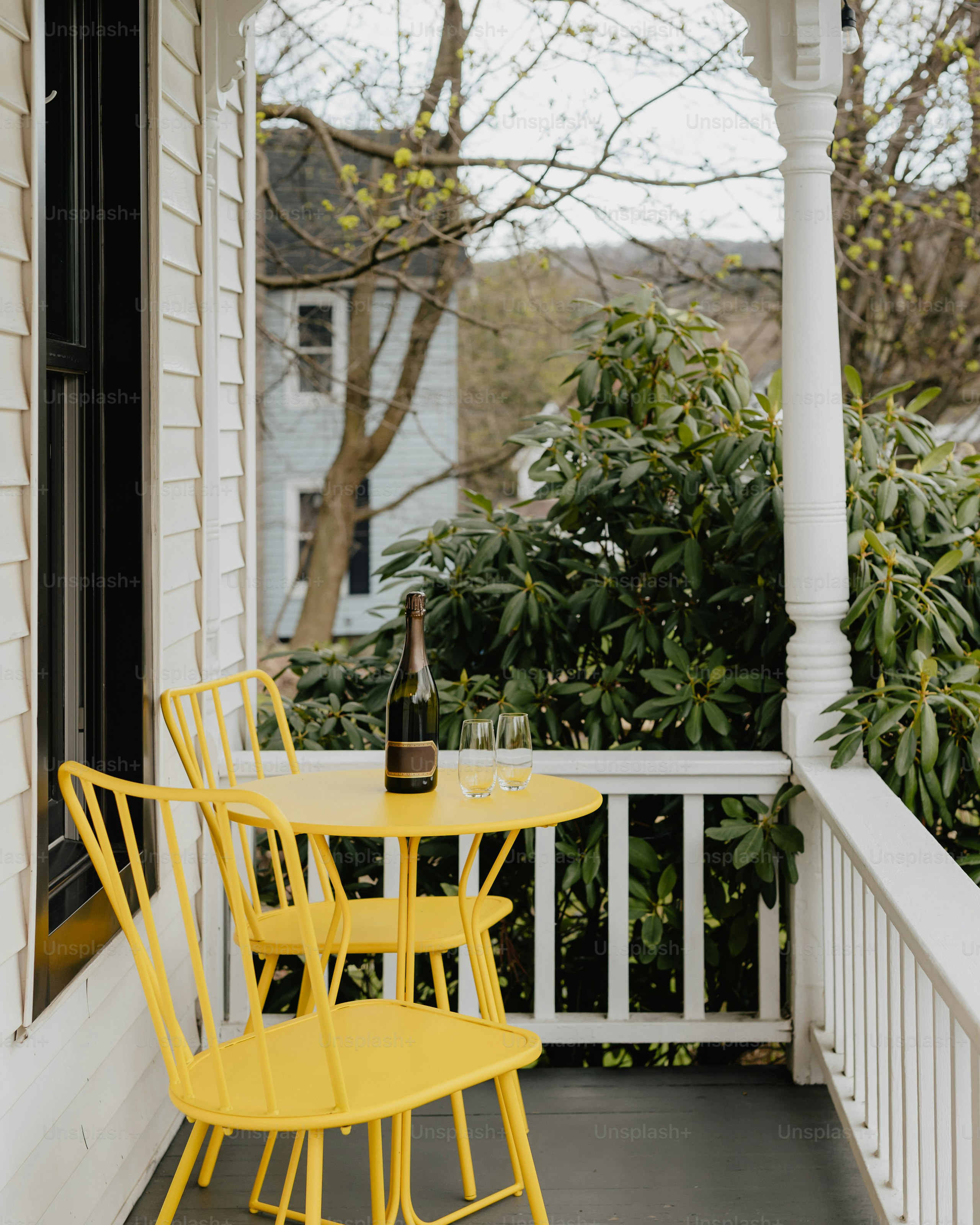 Yellow chairs and table on a porch with champagne.