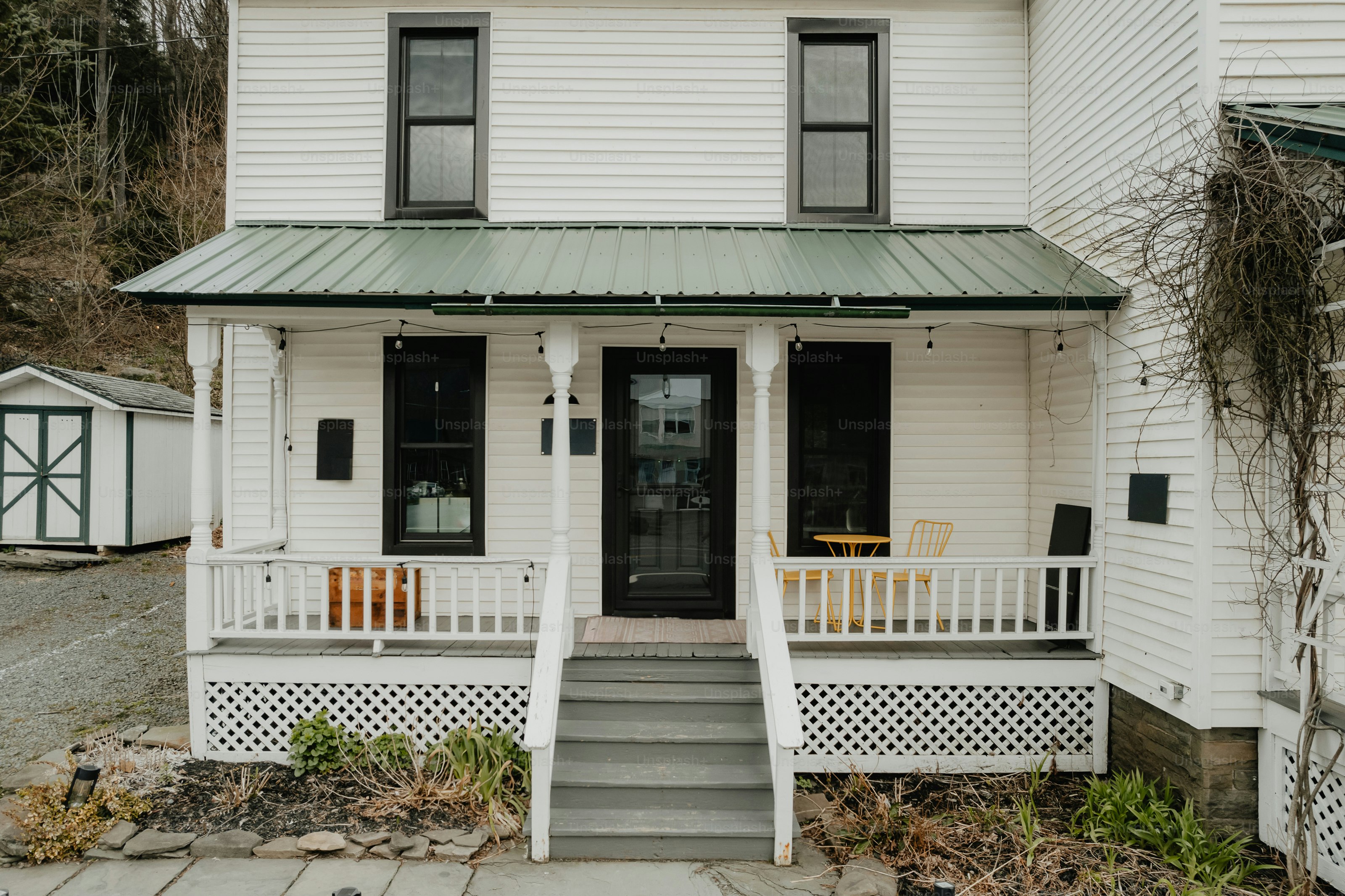 White farmhouse with a green metal roof and porch. photo – House Image ...