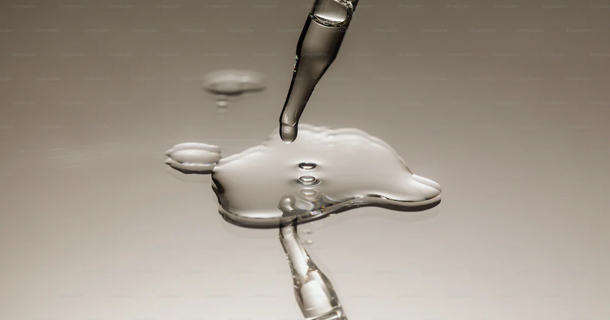 A pipette dripping liquid onto a reflective surface. photo – Macro ...