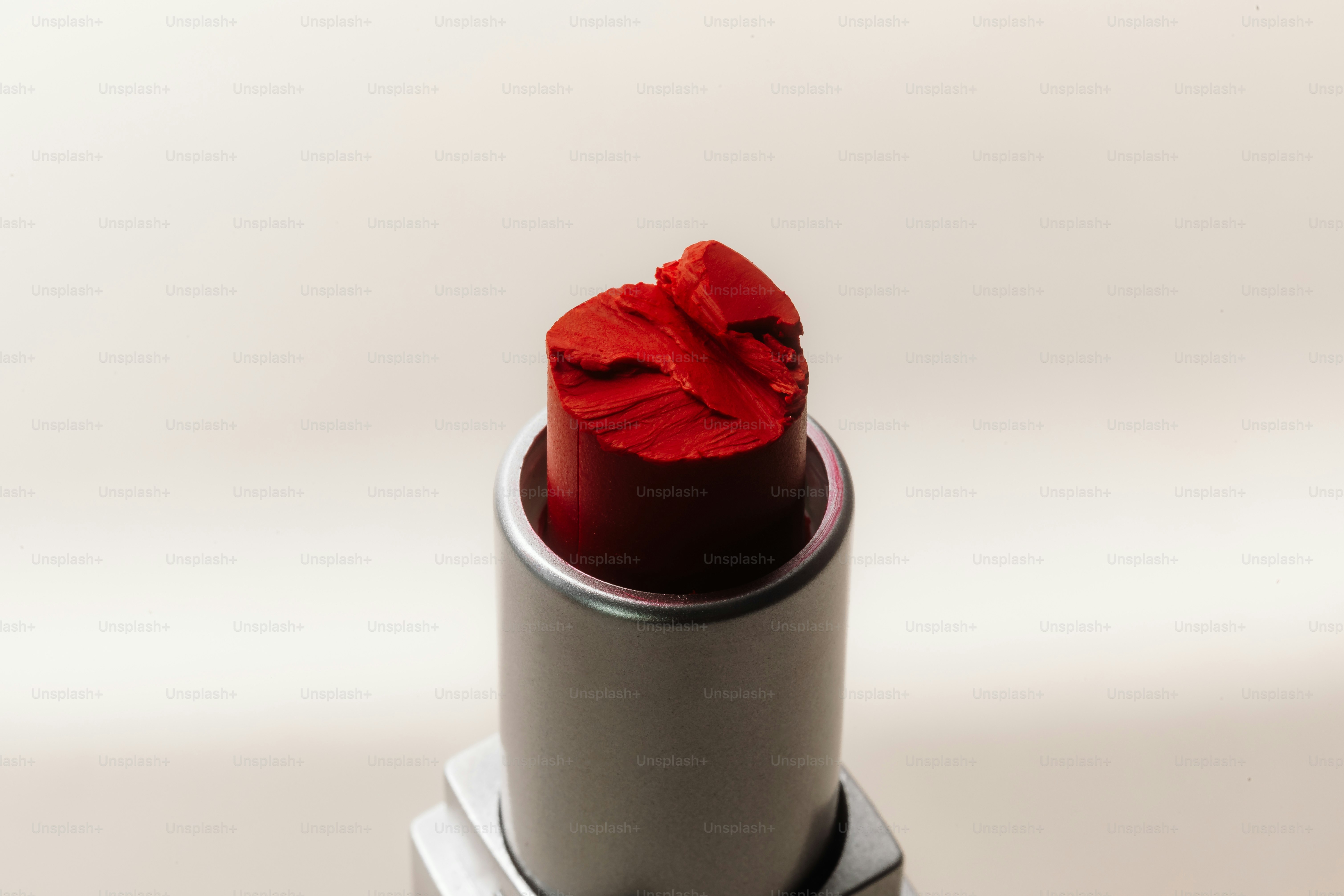 Primer plano de un lápiz labial rojo roto sobre un fondo blanco.