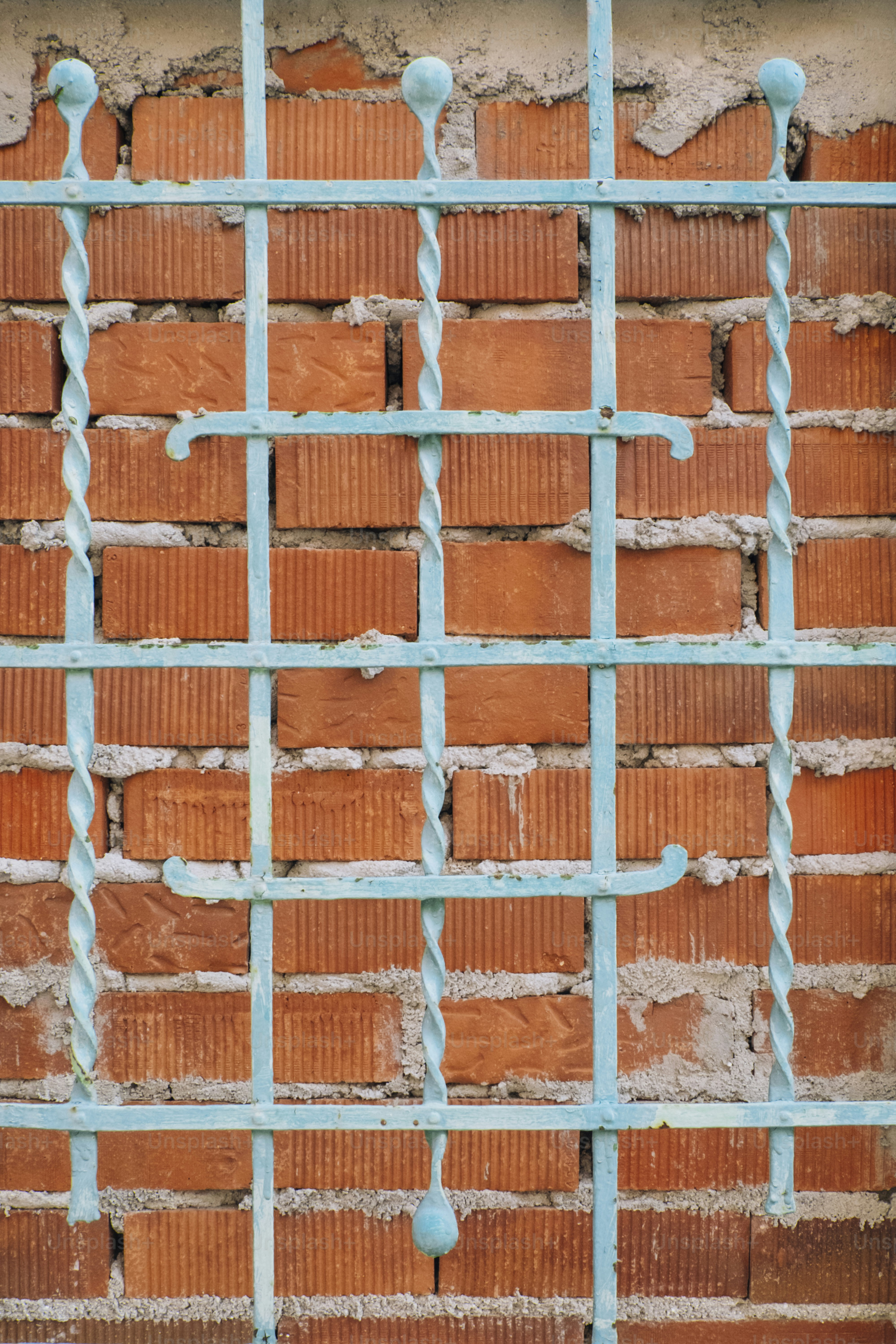 Turquoise metal bars in front of a brick wall