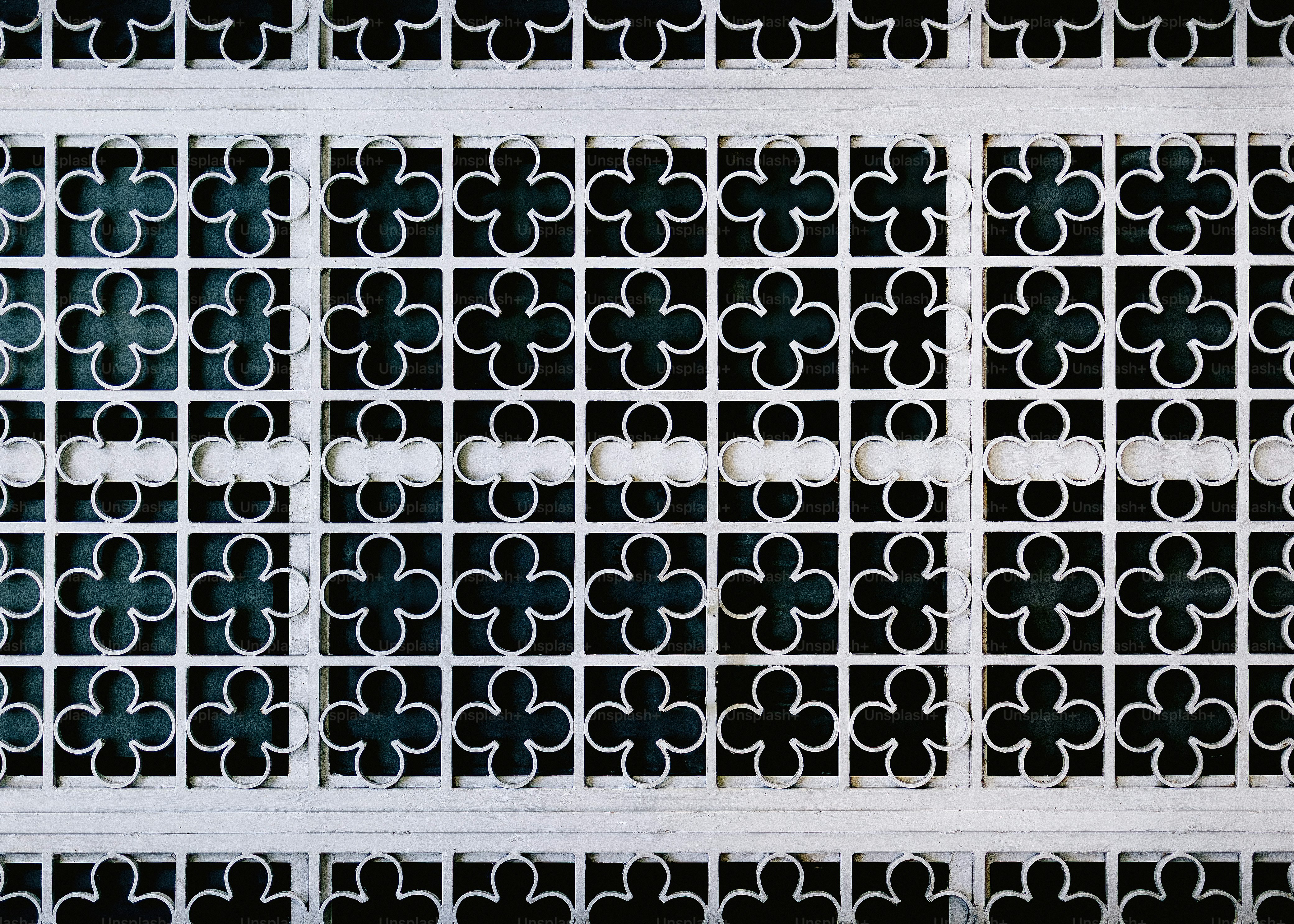 White ornate metal screen with repeating clover pattern