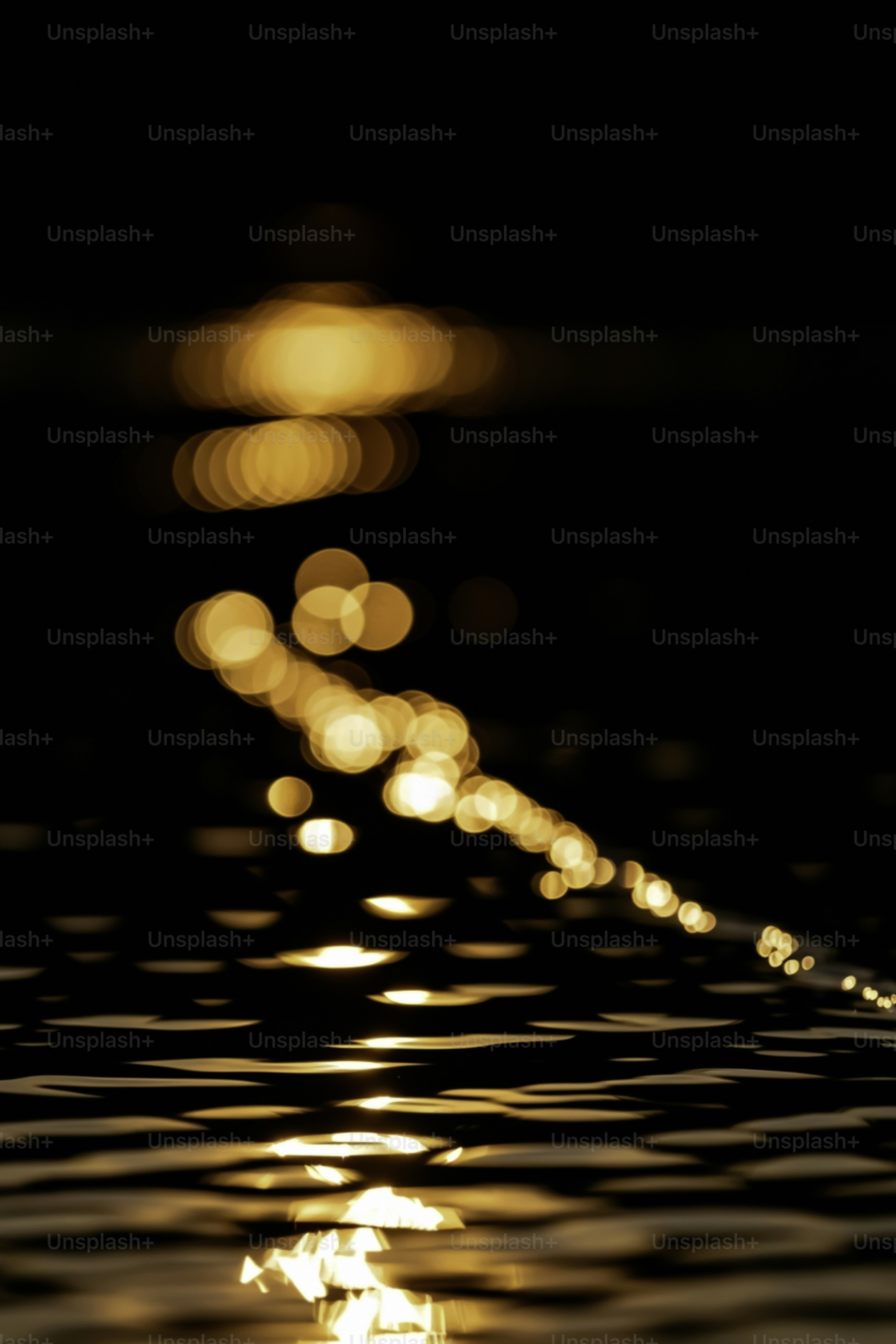 Goldenes Bokeh-Licht, das sich auf dunkler Wasseroberfläche spiegelt