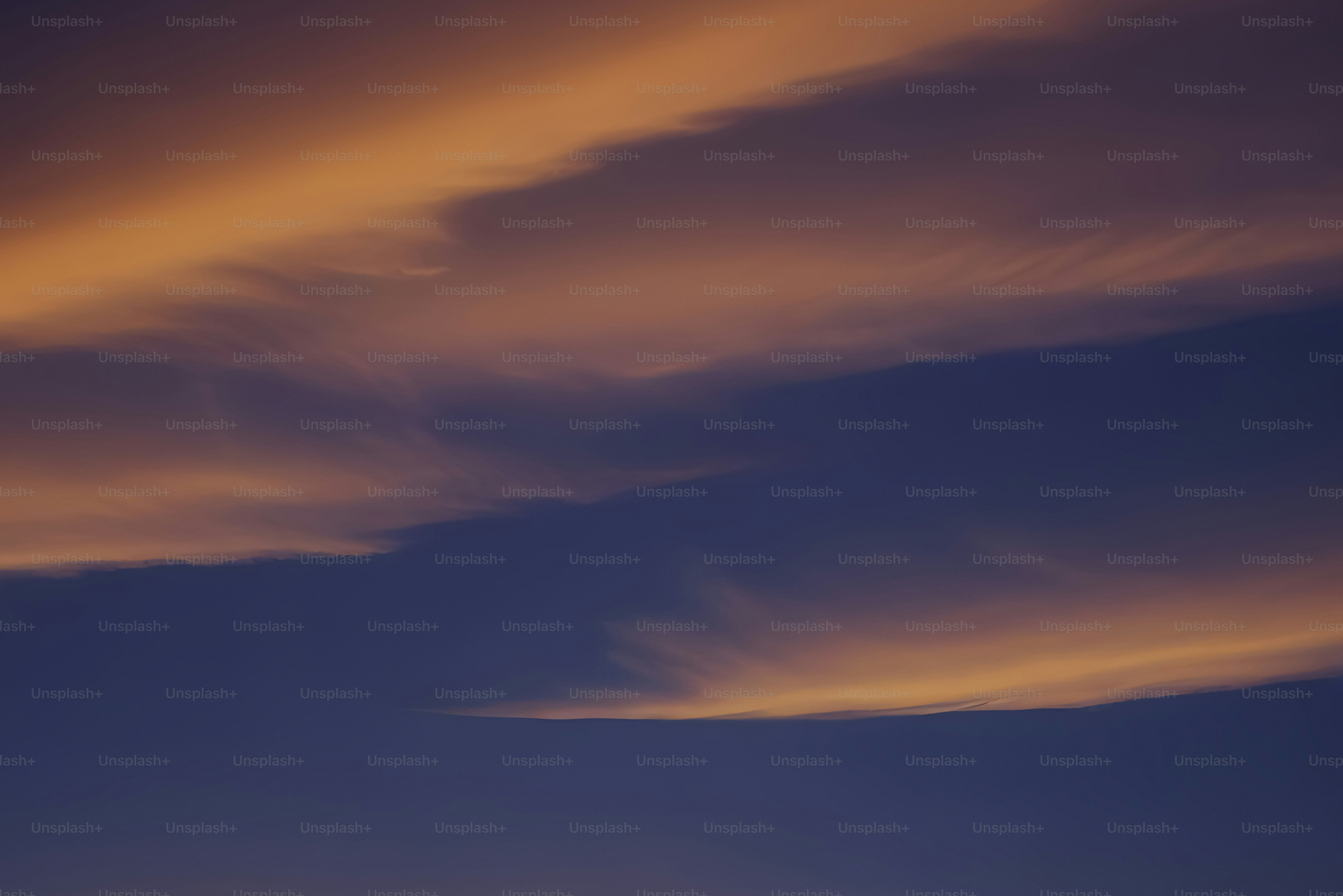 Wispy clouds glow orange against a dark blue sky