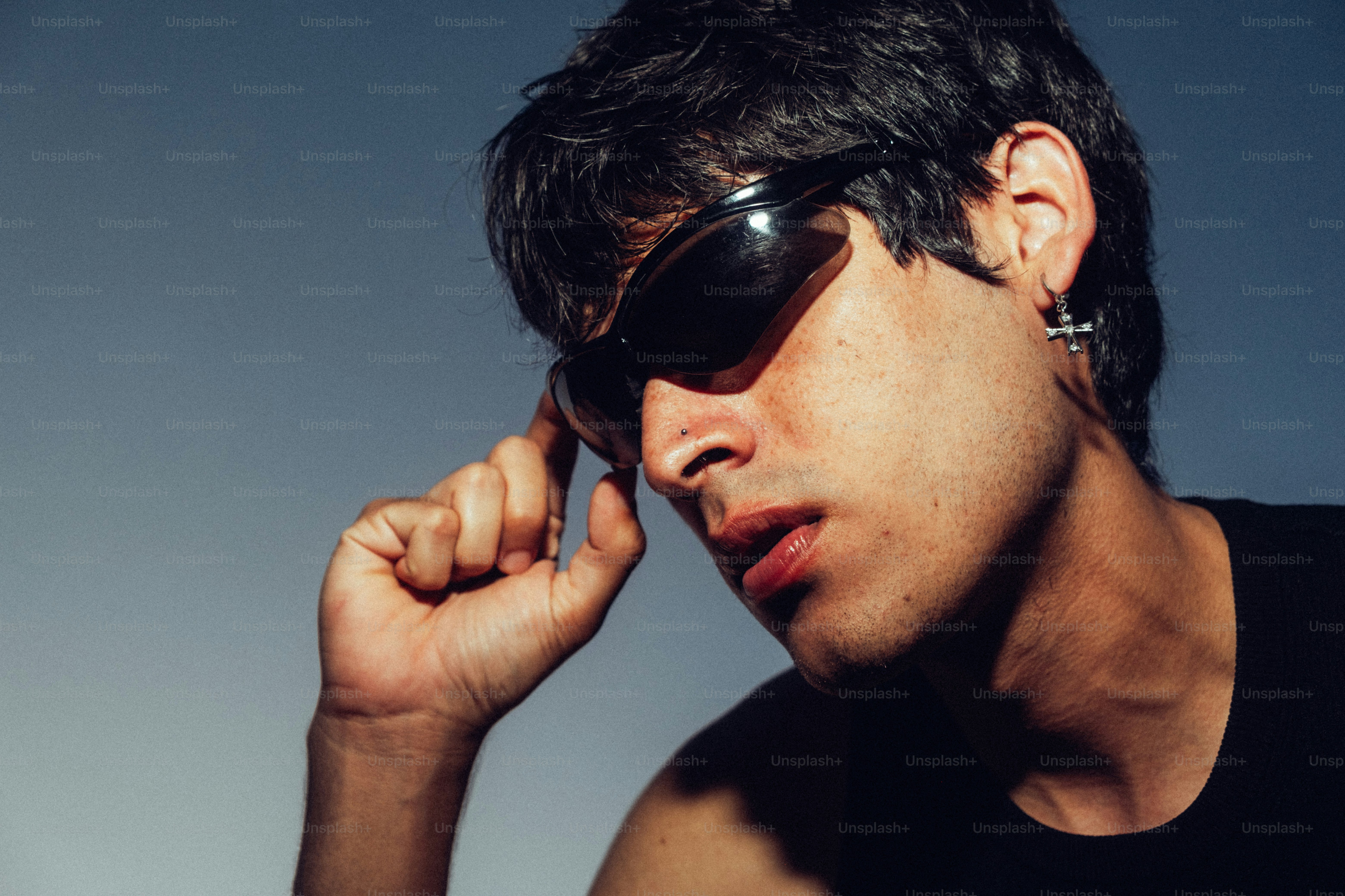 Hombre con gafas de sol ajustándolas con la mano.
