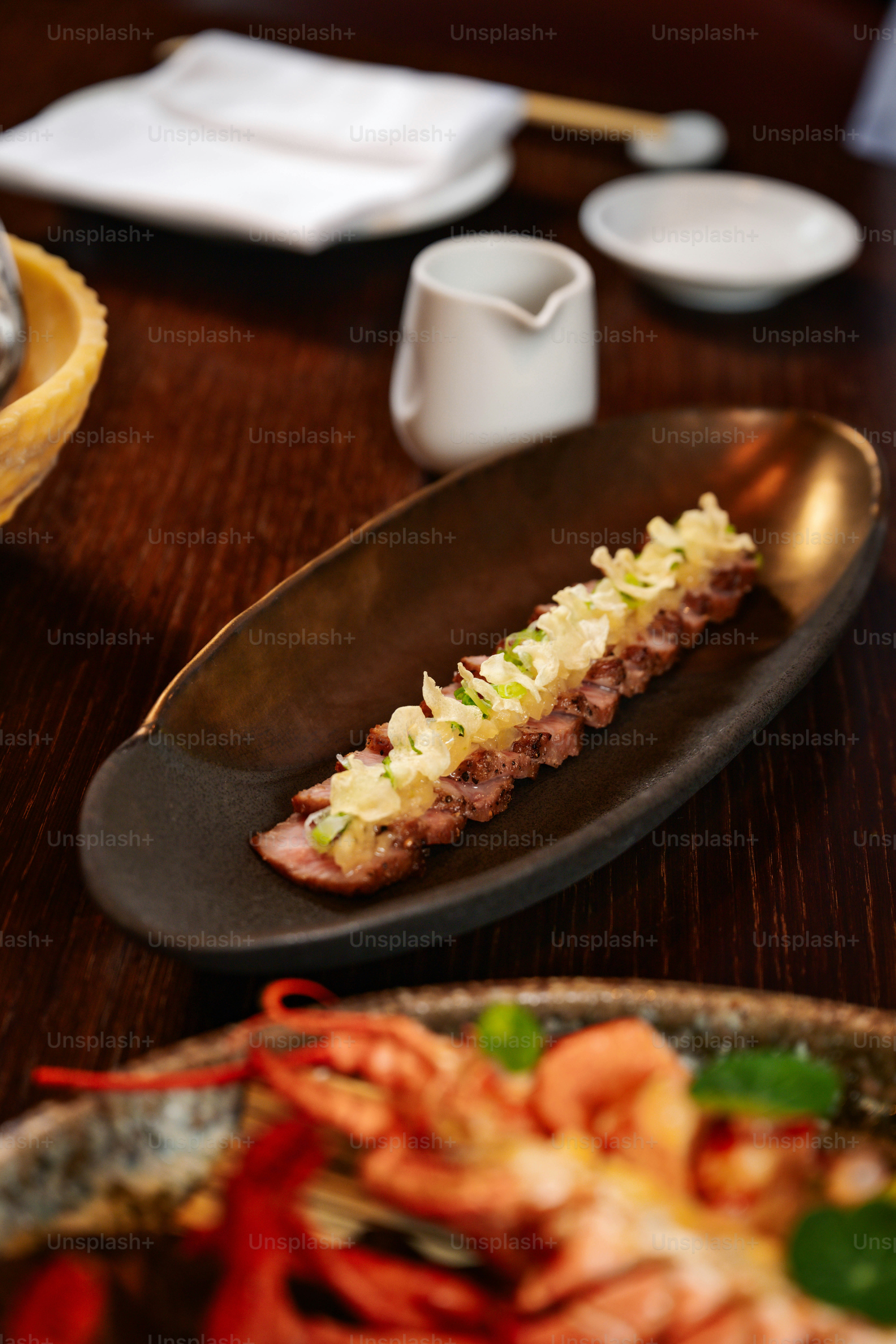 Geschnittenes Rindfleisch mit Frühlingszwiebeln auf einem dunklen Teller