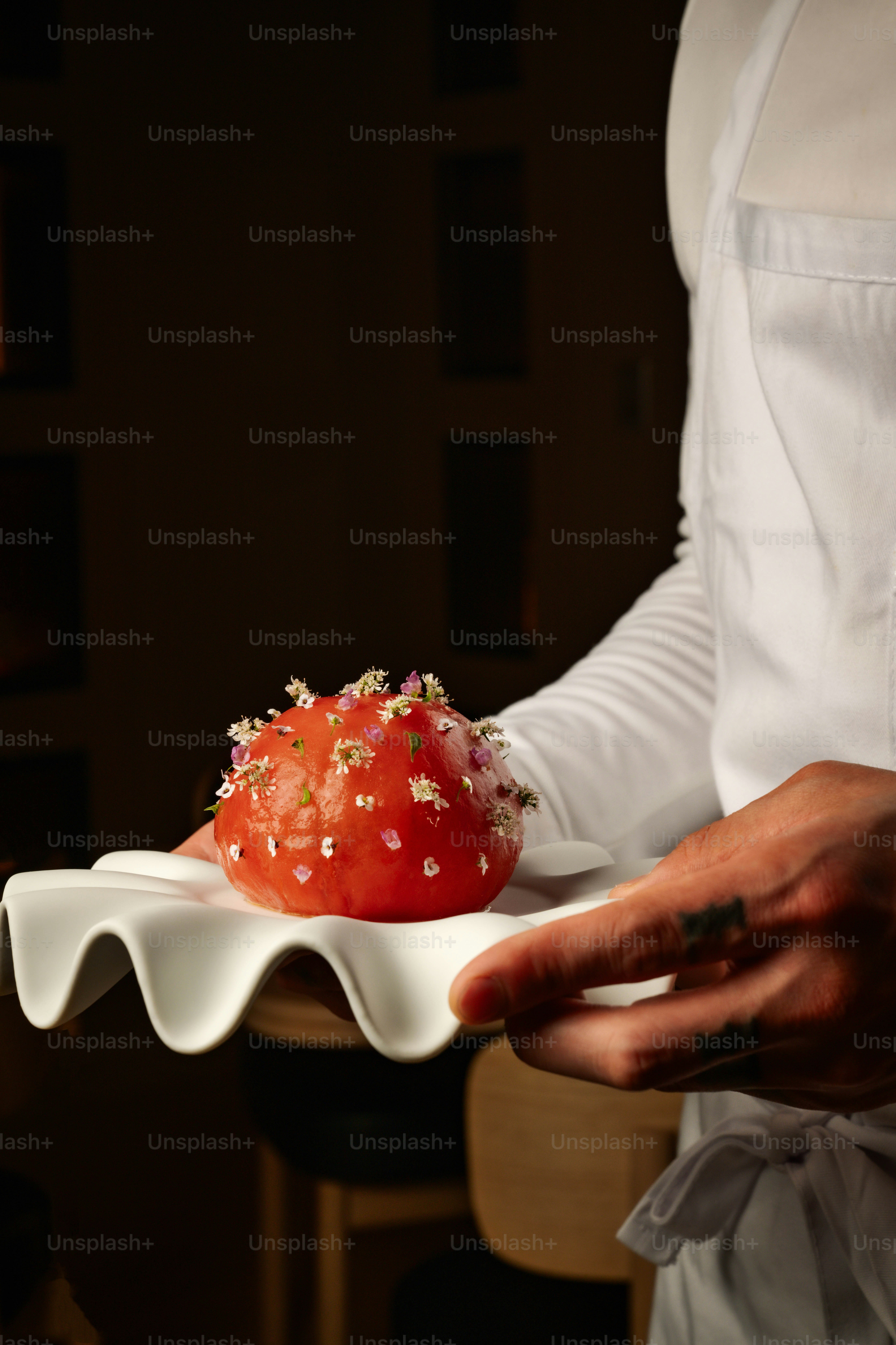 Der Küchenchef präsentiert eine Tomate, die mit kleinen Blüten garniert ist