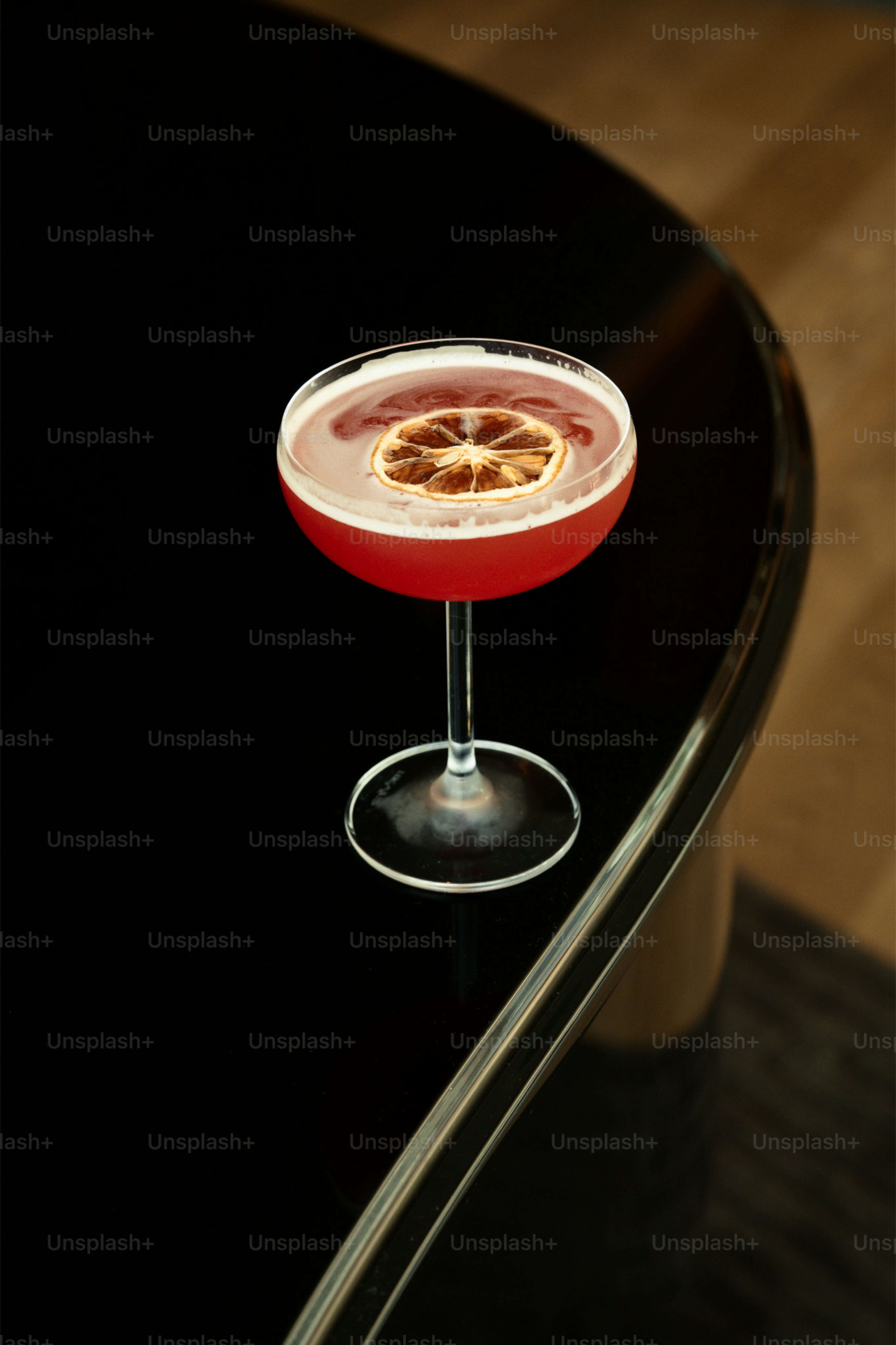 Coquetel vermelho com guarnição de fatia de laranja seca.