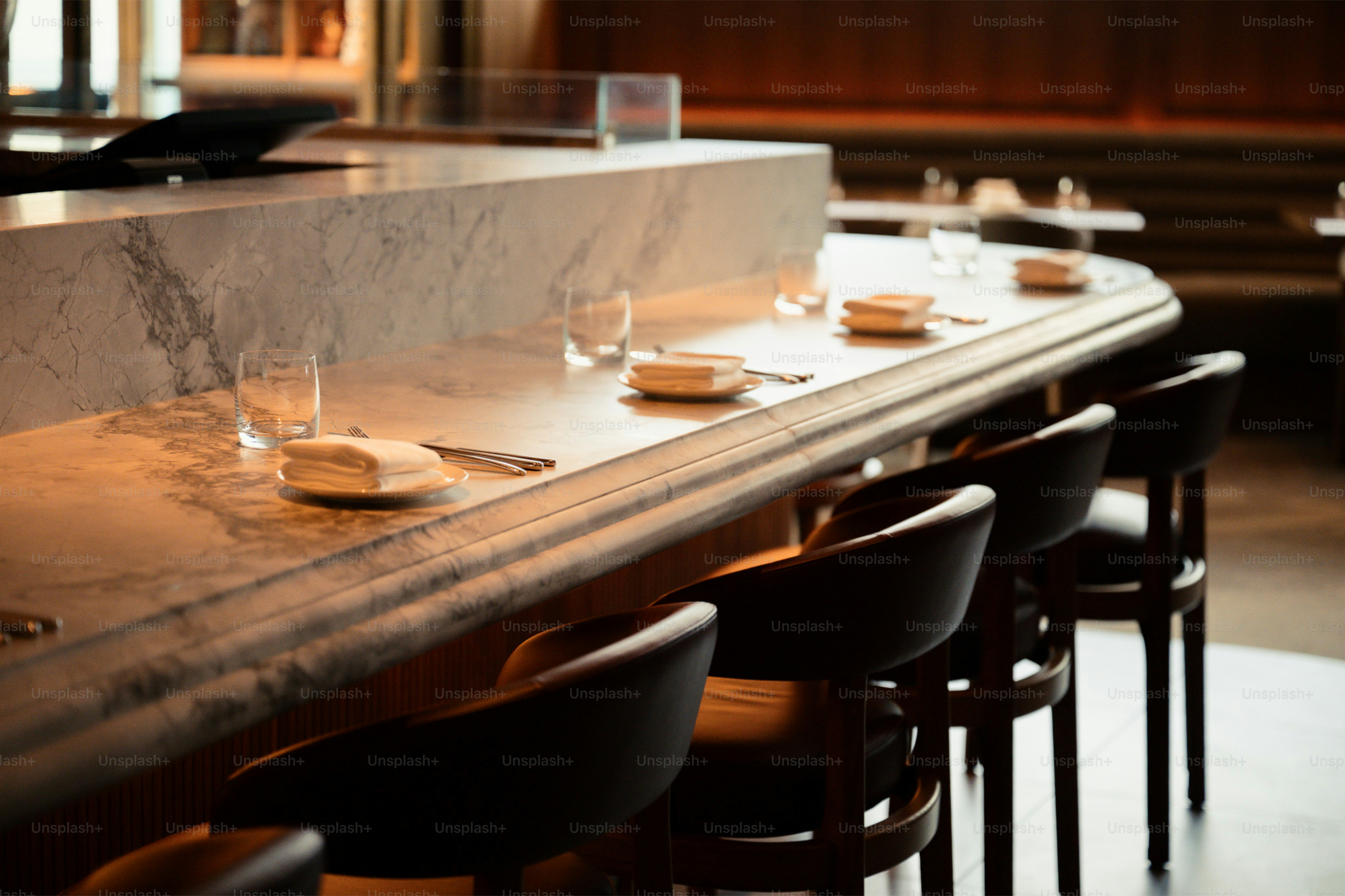 A modern bar with marble countertop and seating.