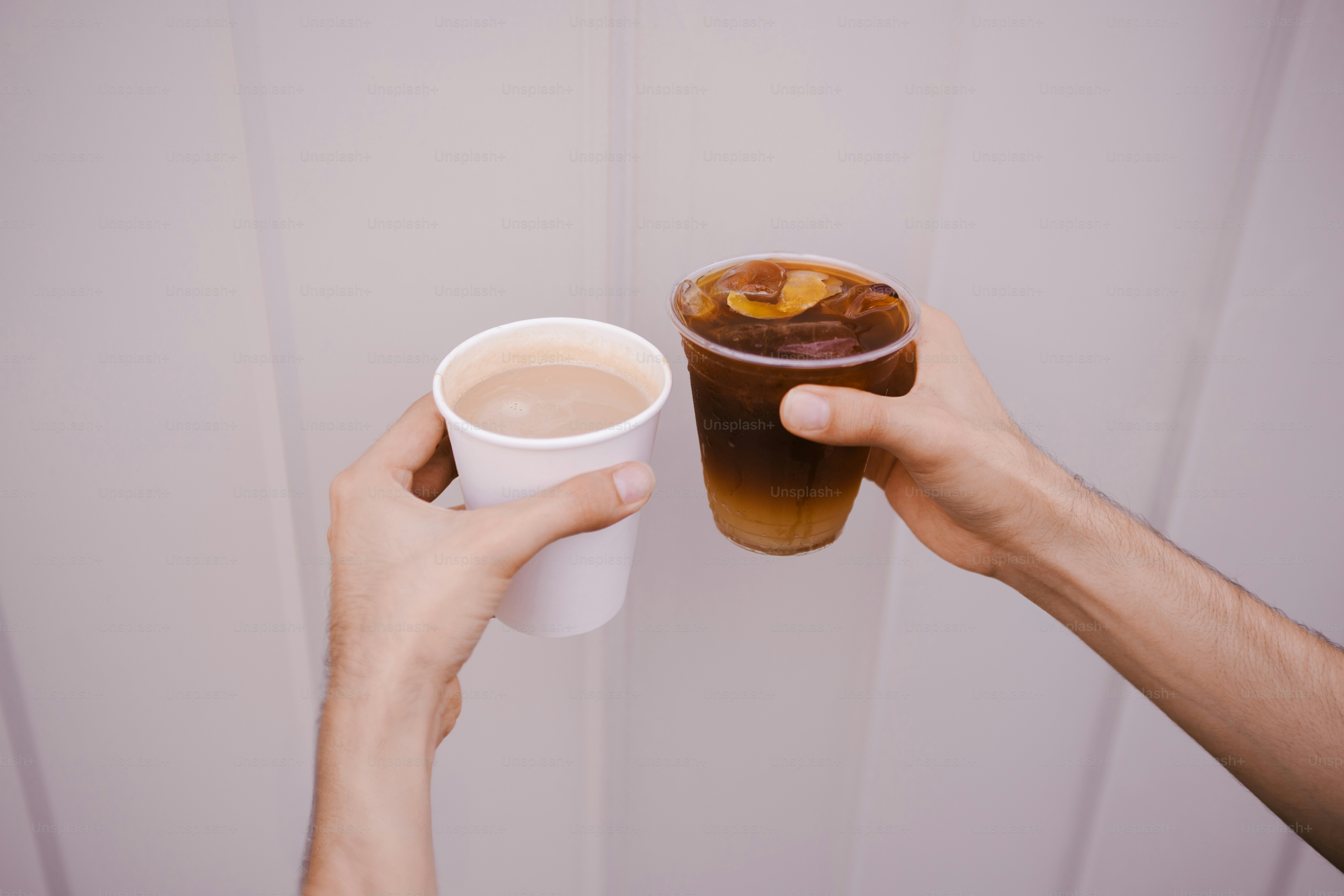 Two hands holding coffee cups in a toast.