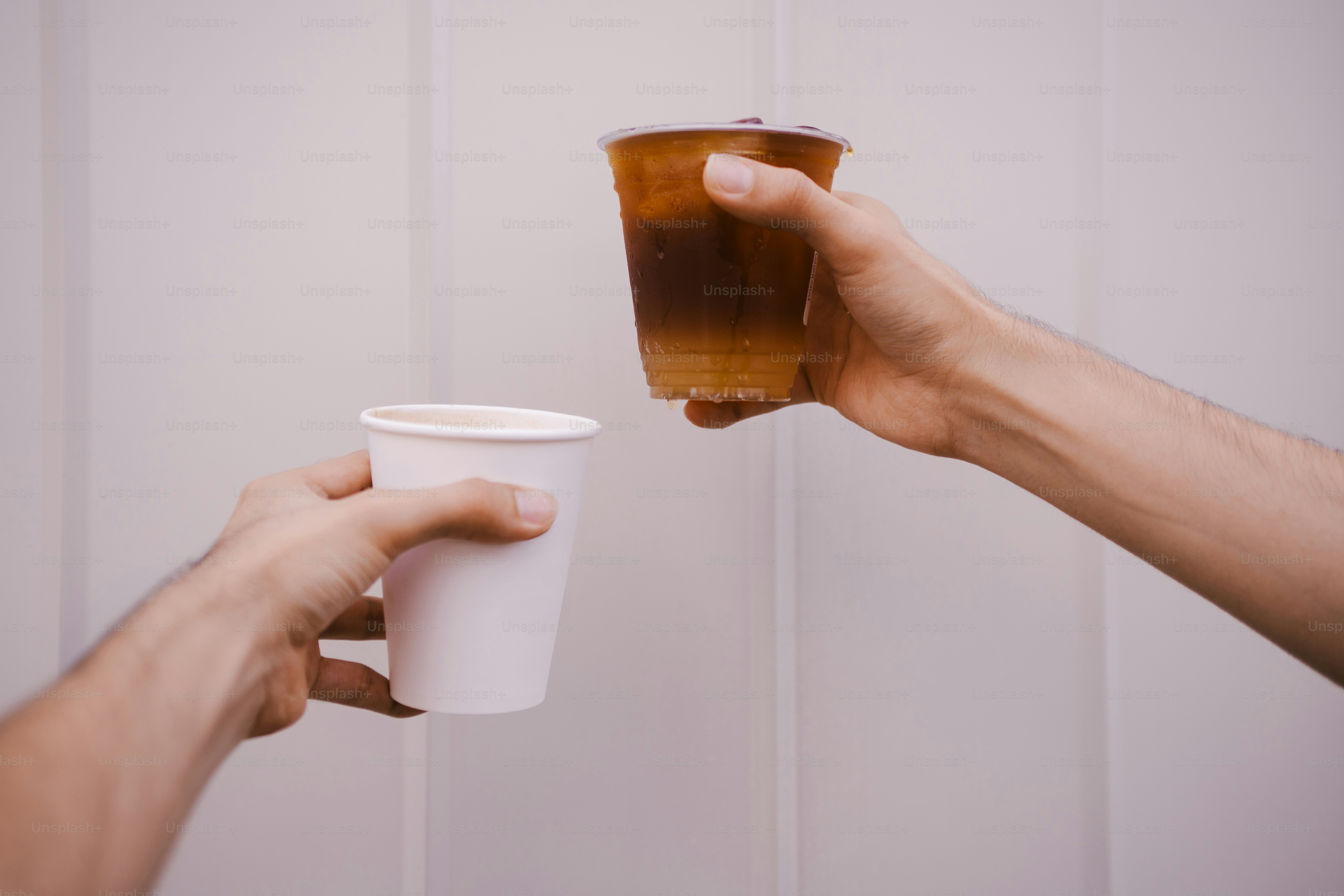 Dua tangan memegang cangkir kopi dengan latar belakang putih.