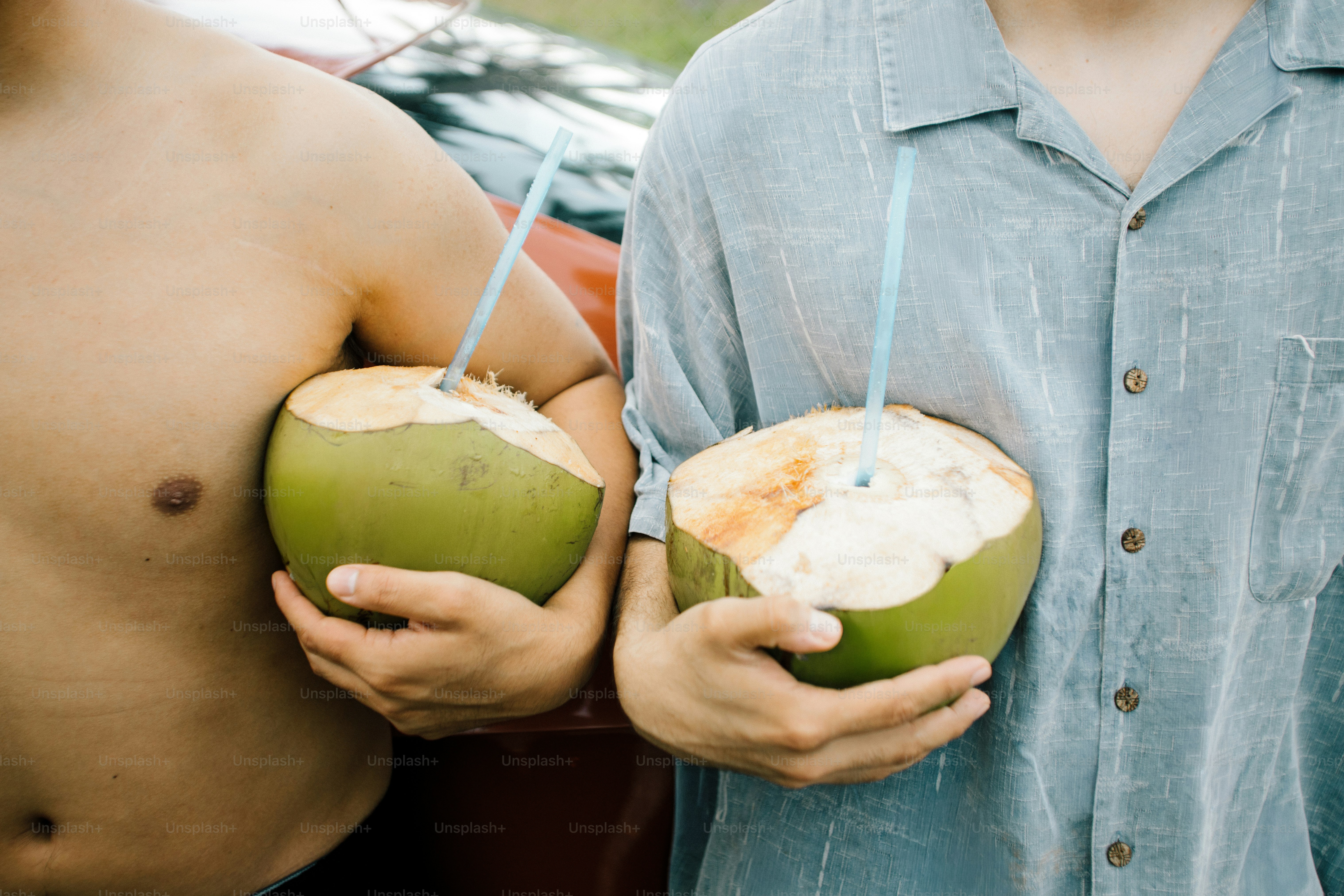 Two people holding coconuts with straws