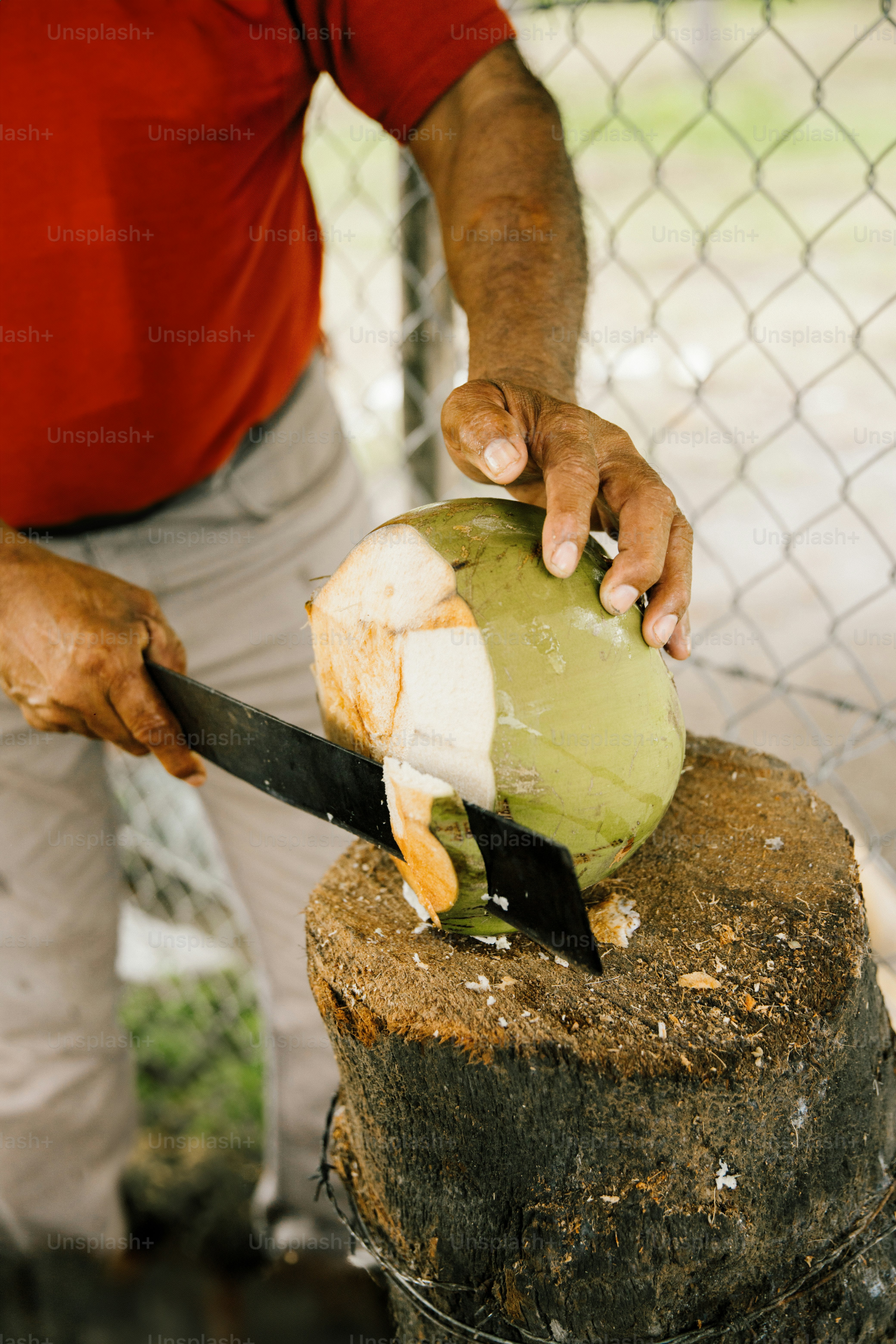 Man opening a fresh coconut with a large knife