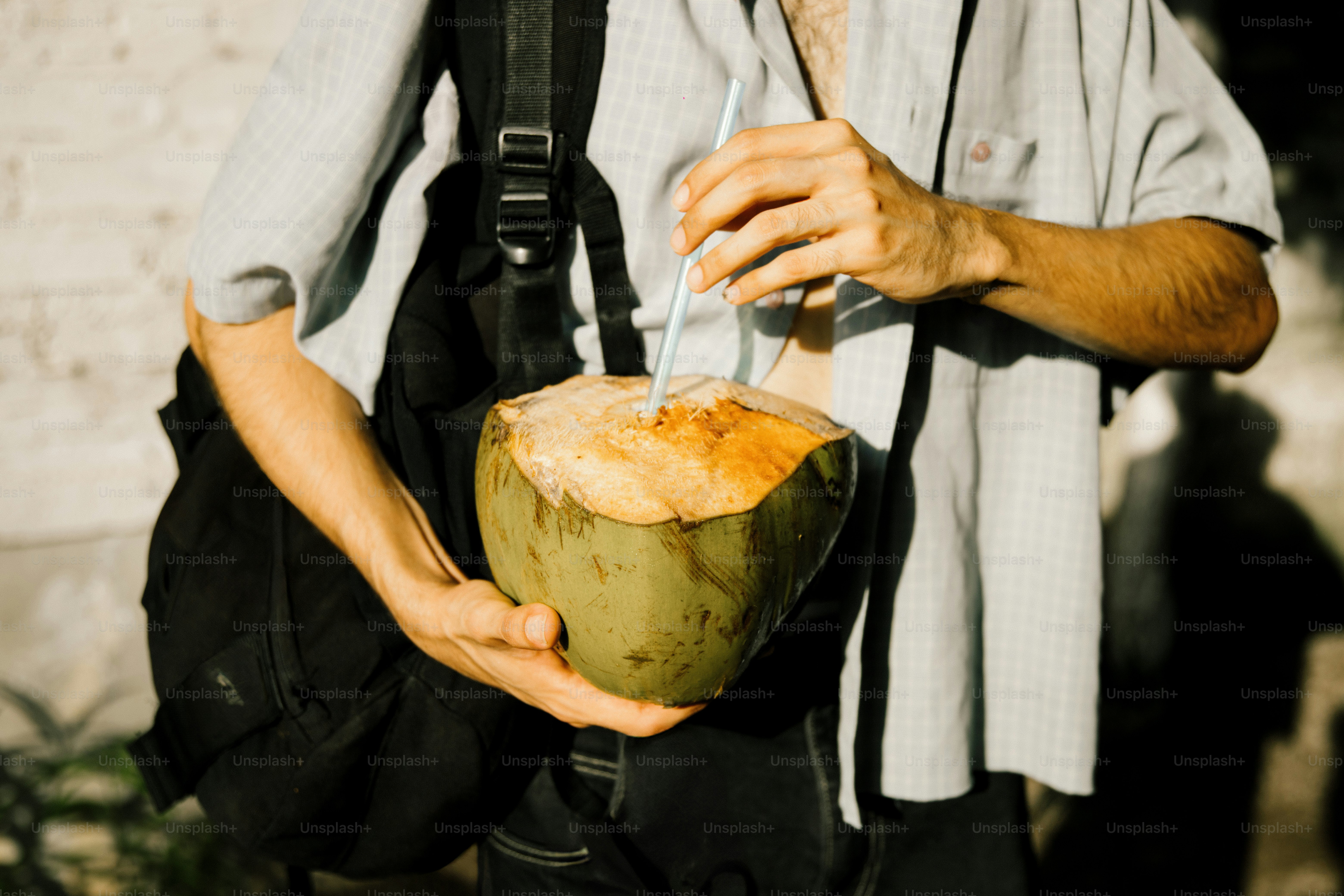 Person holding a fresh coconut with a straw.