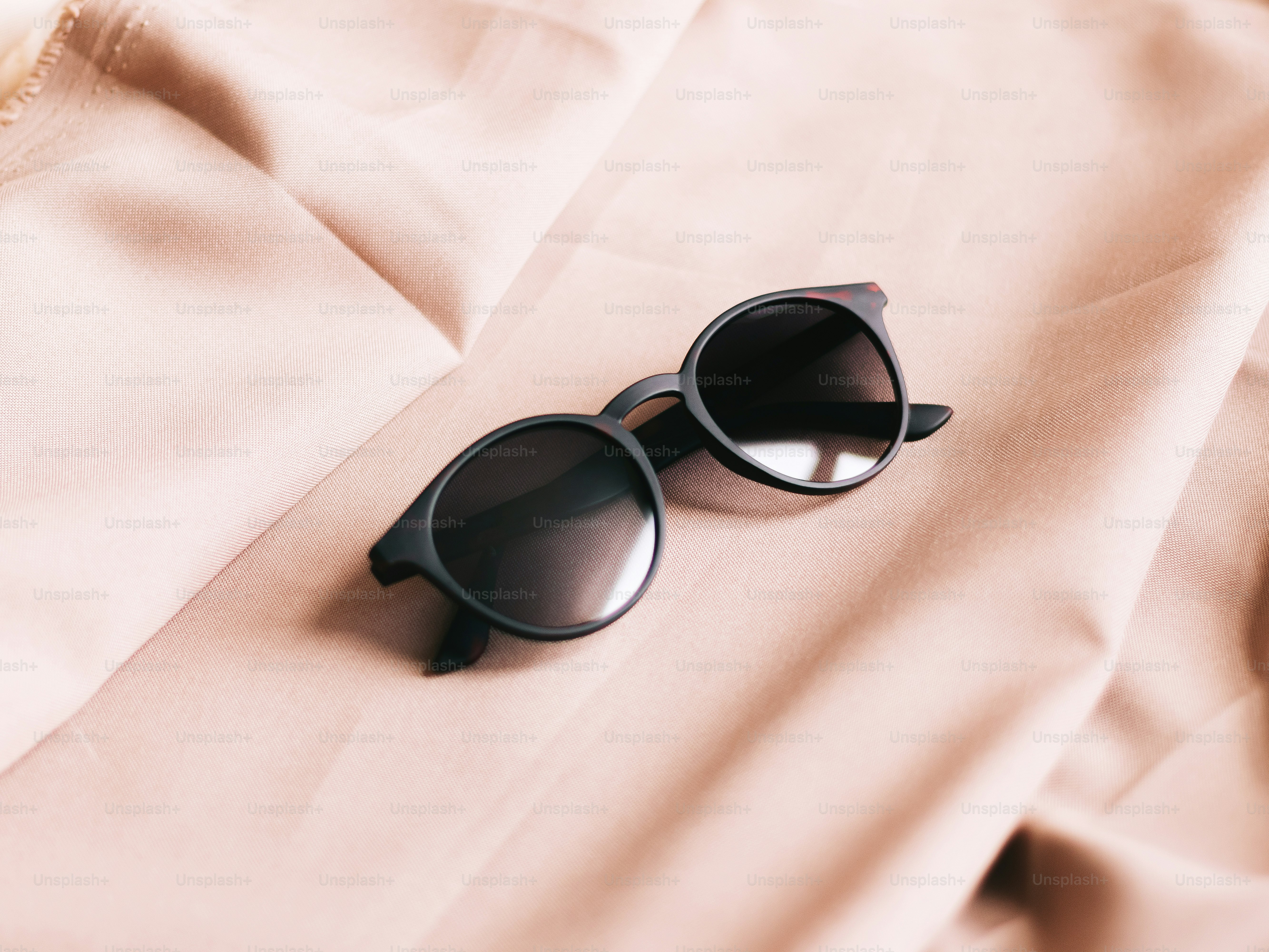 Black sunglasses resting on soft pink fabric