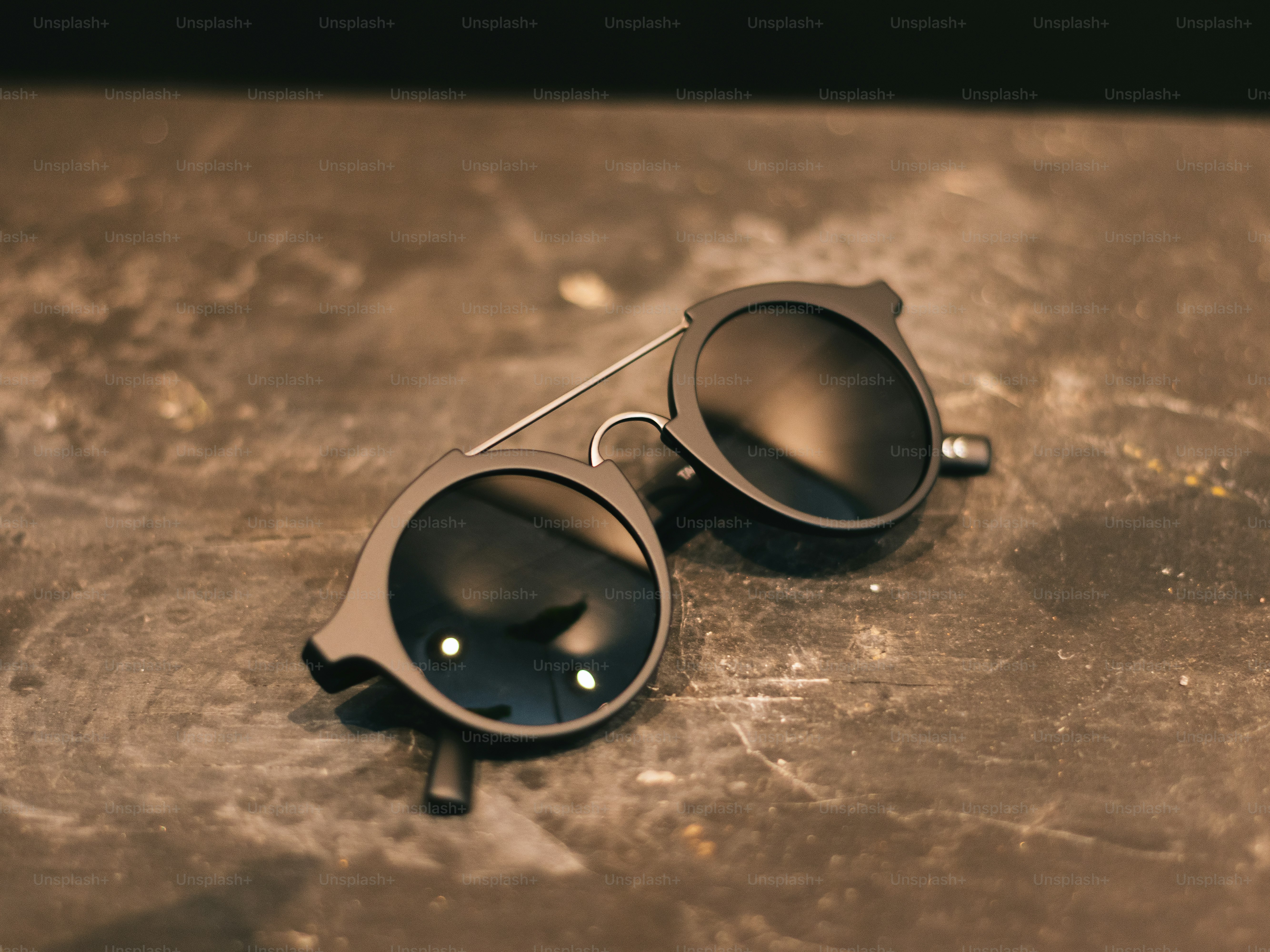 Stilvolle runde Sonnenbrille, die auf einer strukturierten Oberfläche ruht