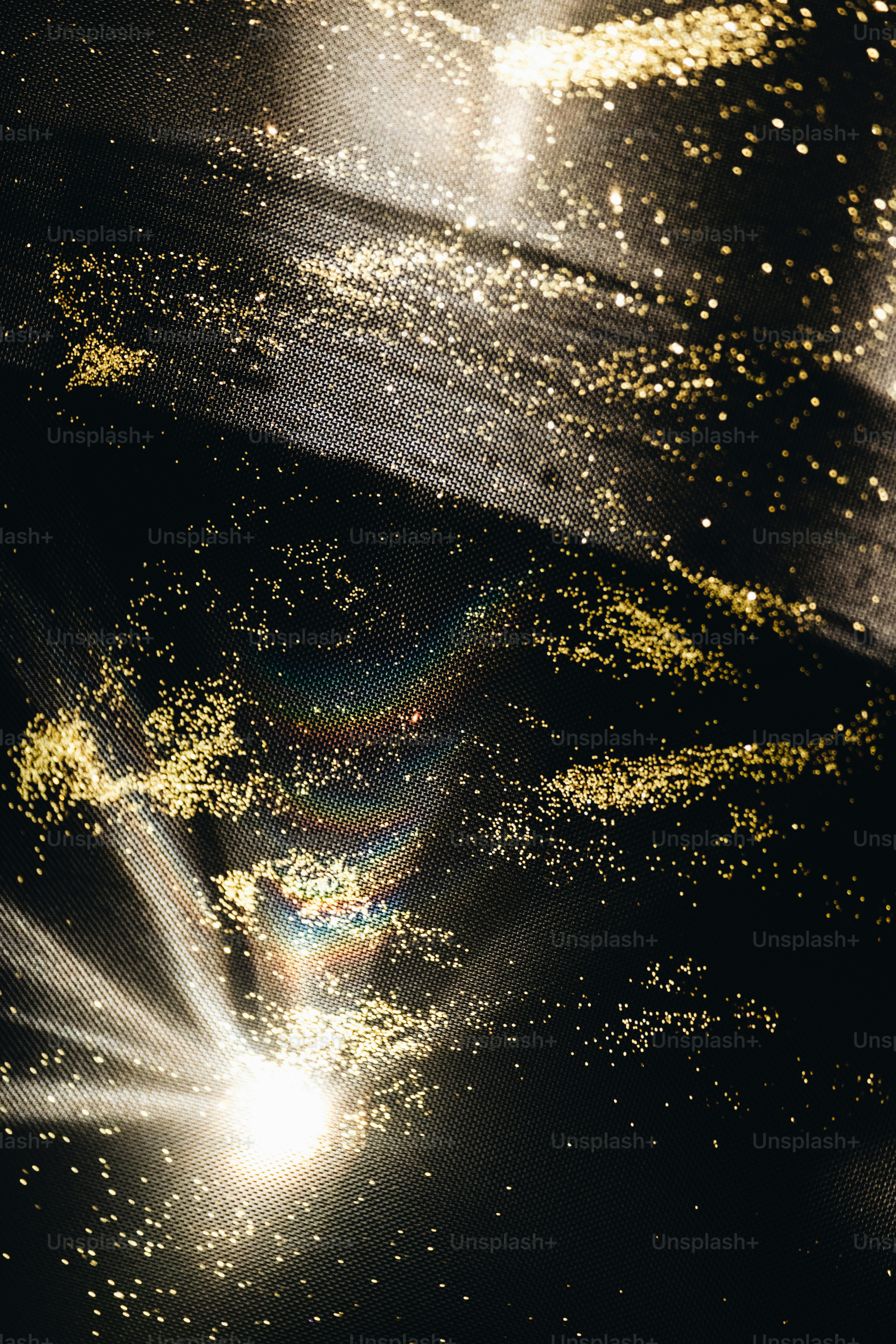 Golden glitter scattered across a dark, textured surface.