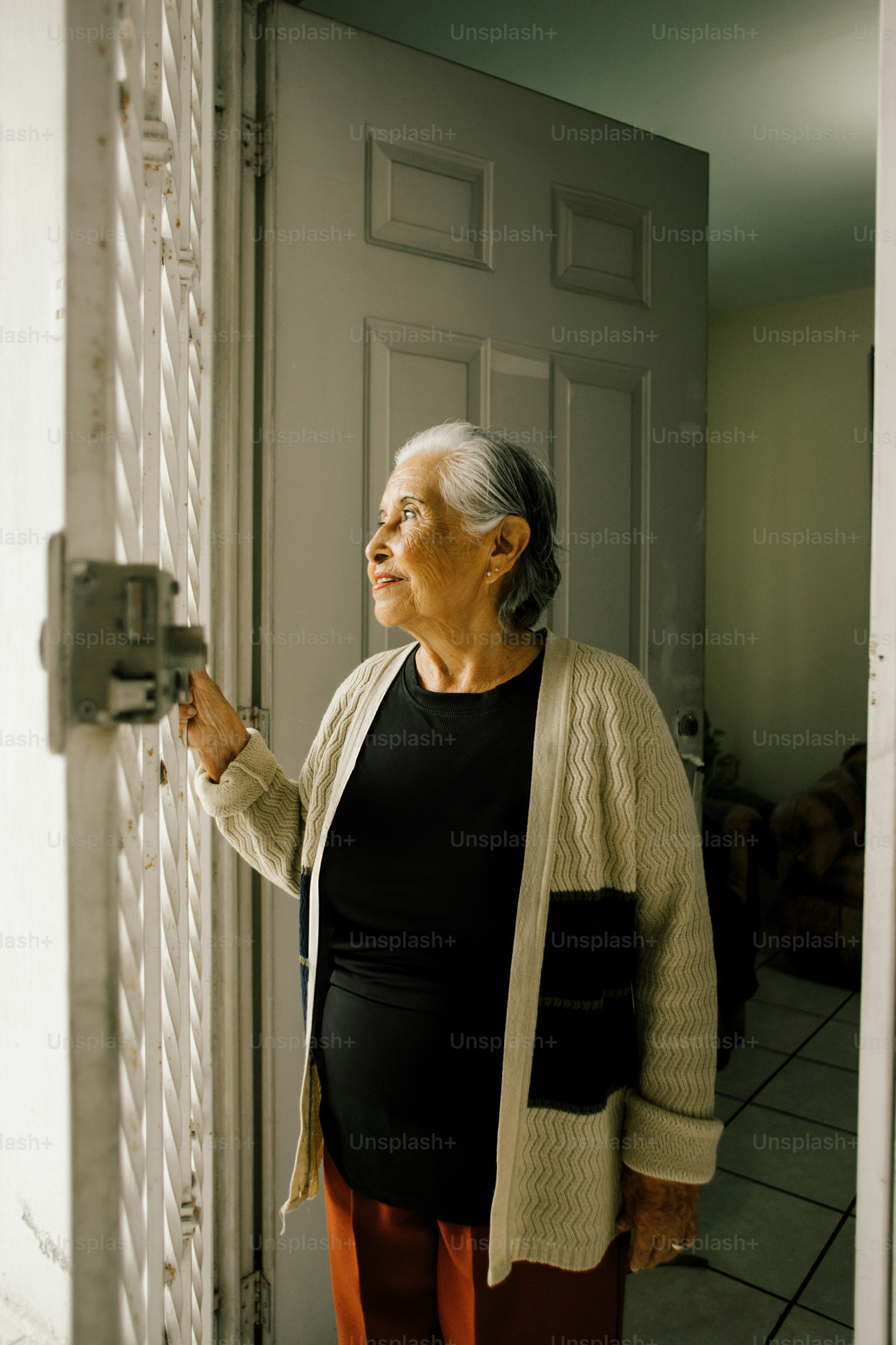 Elderly woman opening a door with a gate