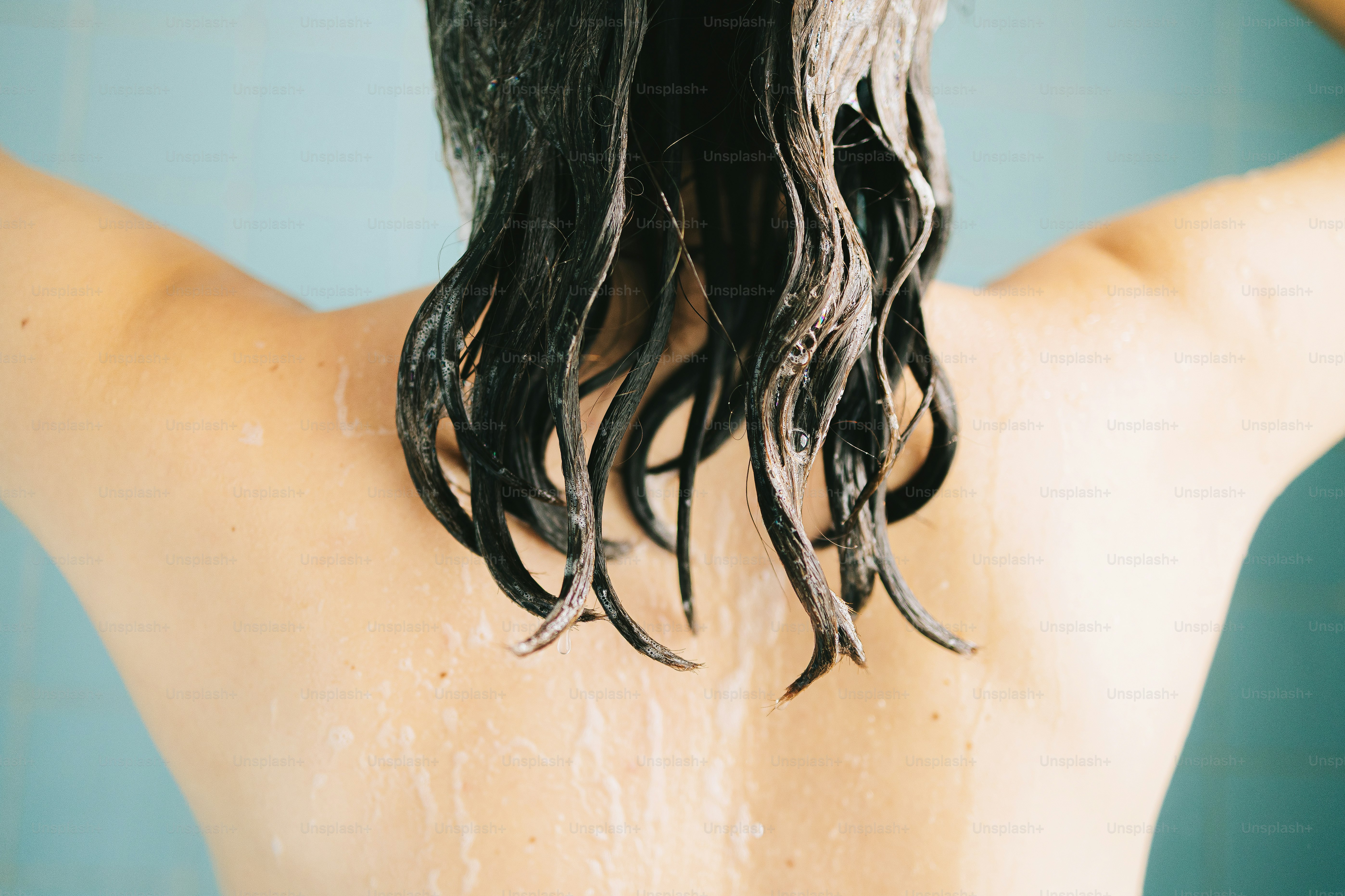 Frau, die ihre nassen Haare unter der Dusche wäscht