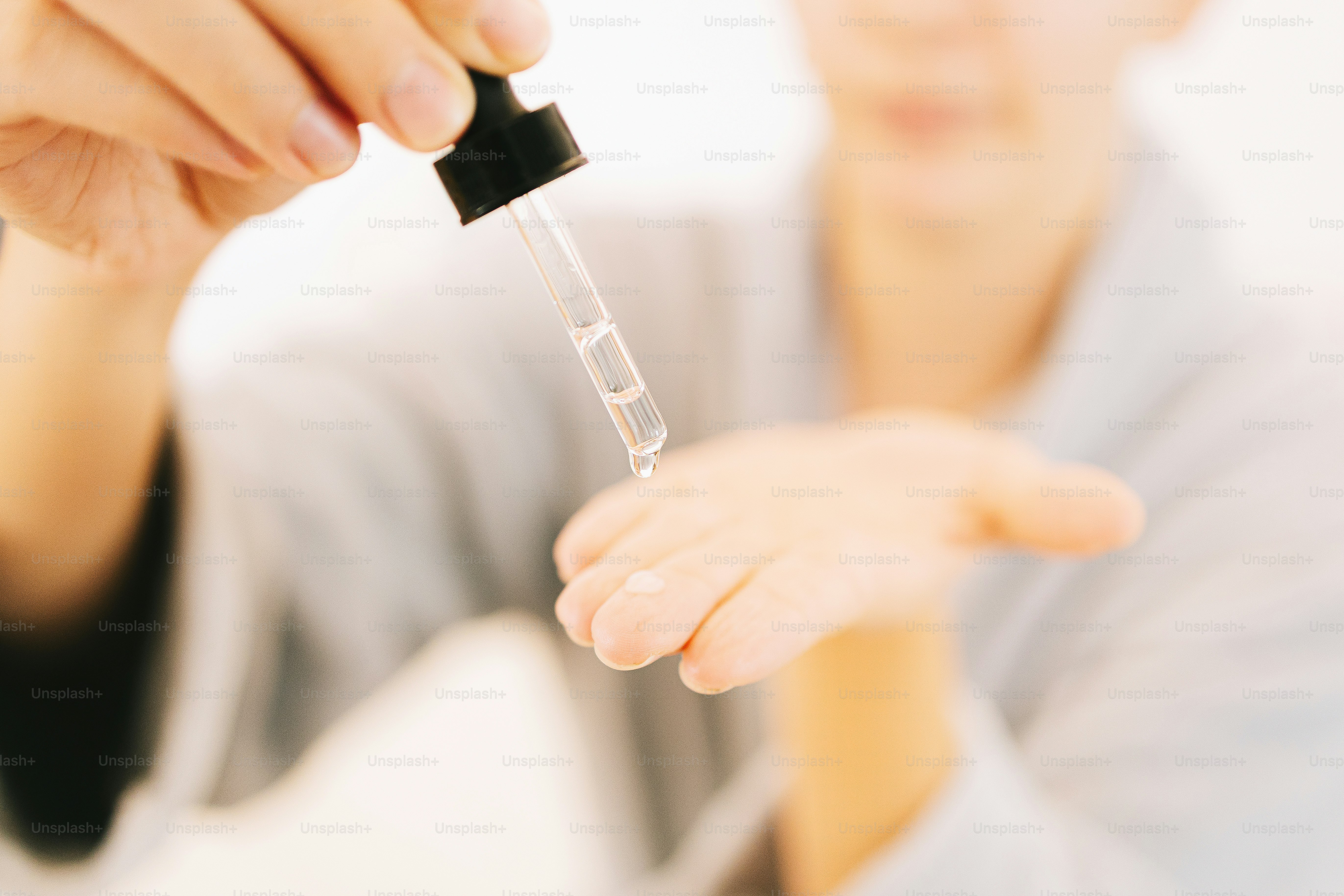 Person, die Serum aus der Pipette auf die Hand aufträgt