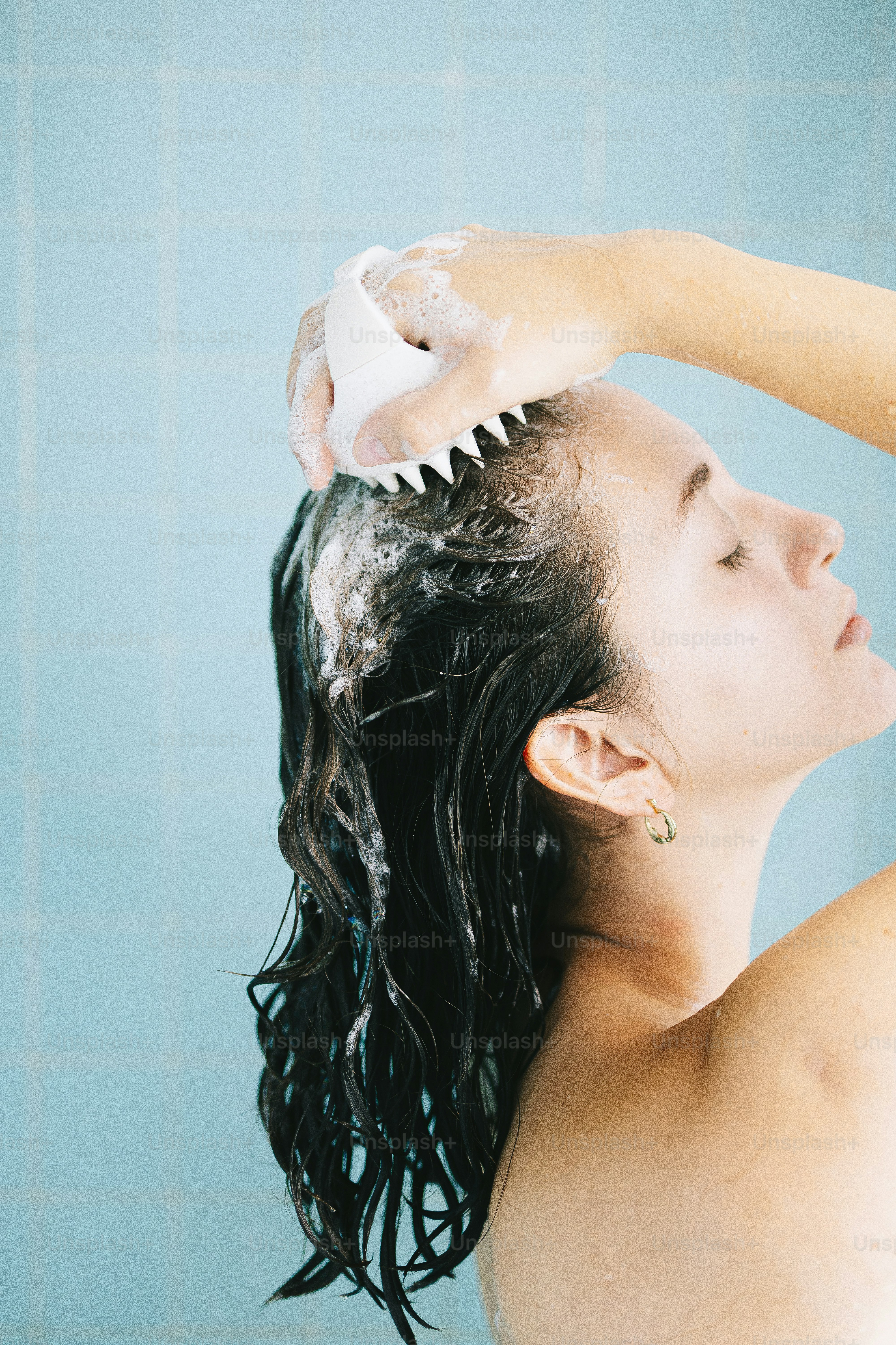 Frau, die Haare mit einem Kopfhautmassagegerät wäscht