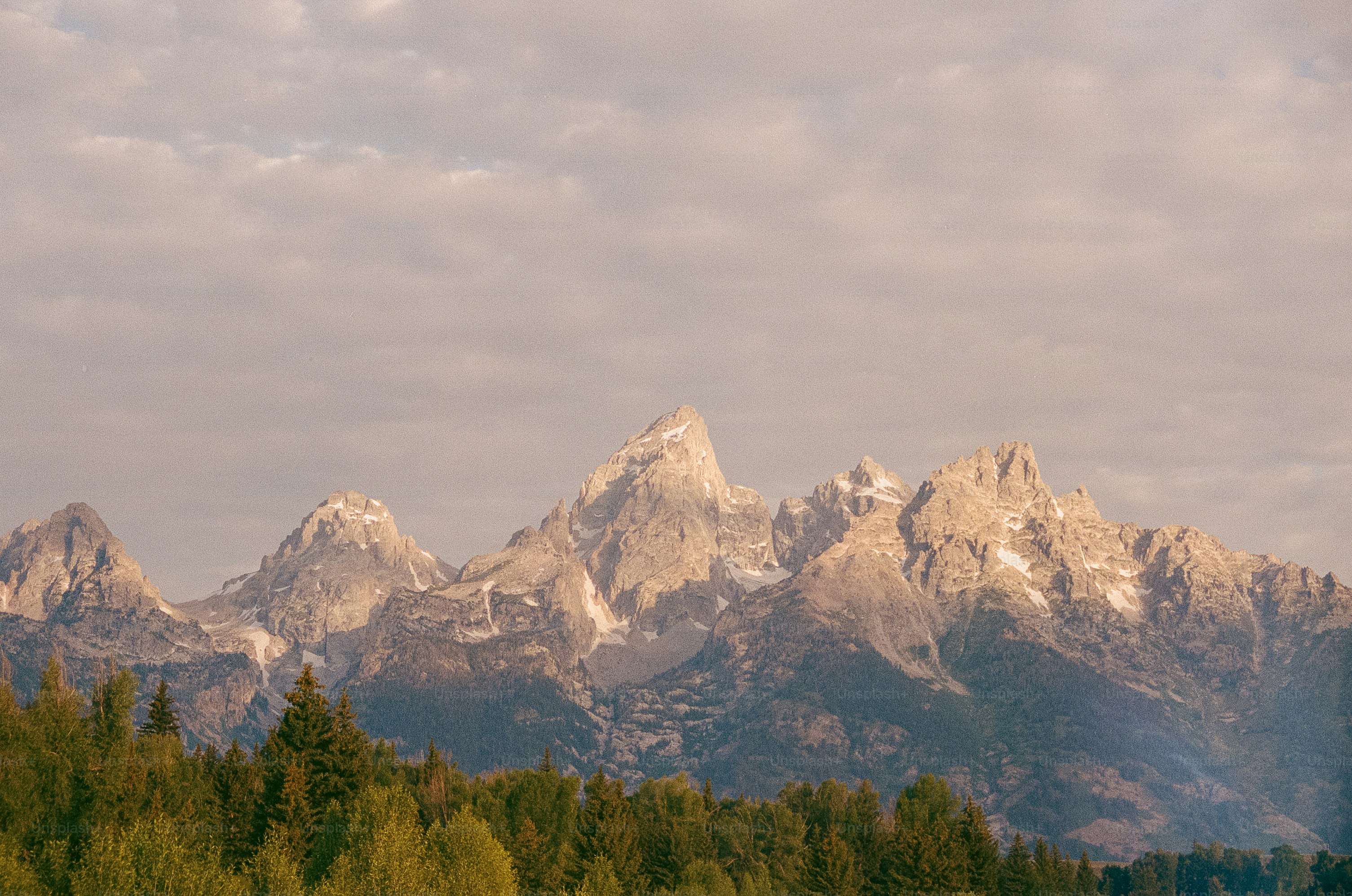 Picos de montanha irregulares com neve sob o céu nublado