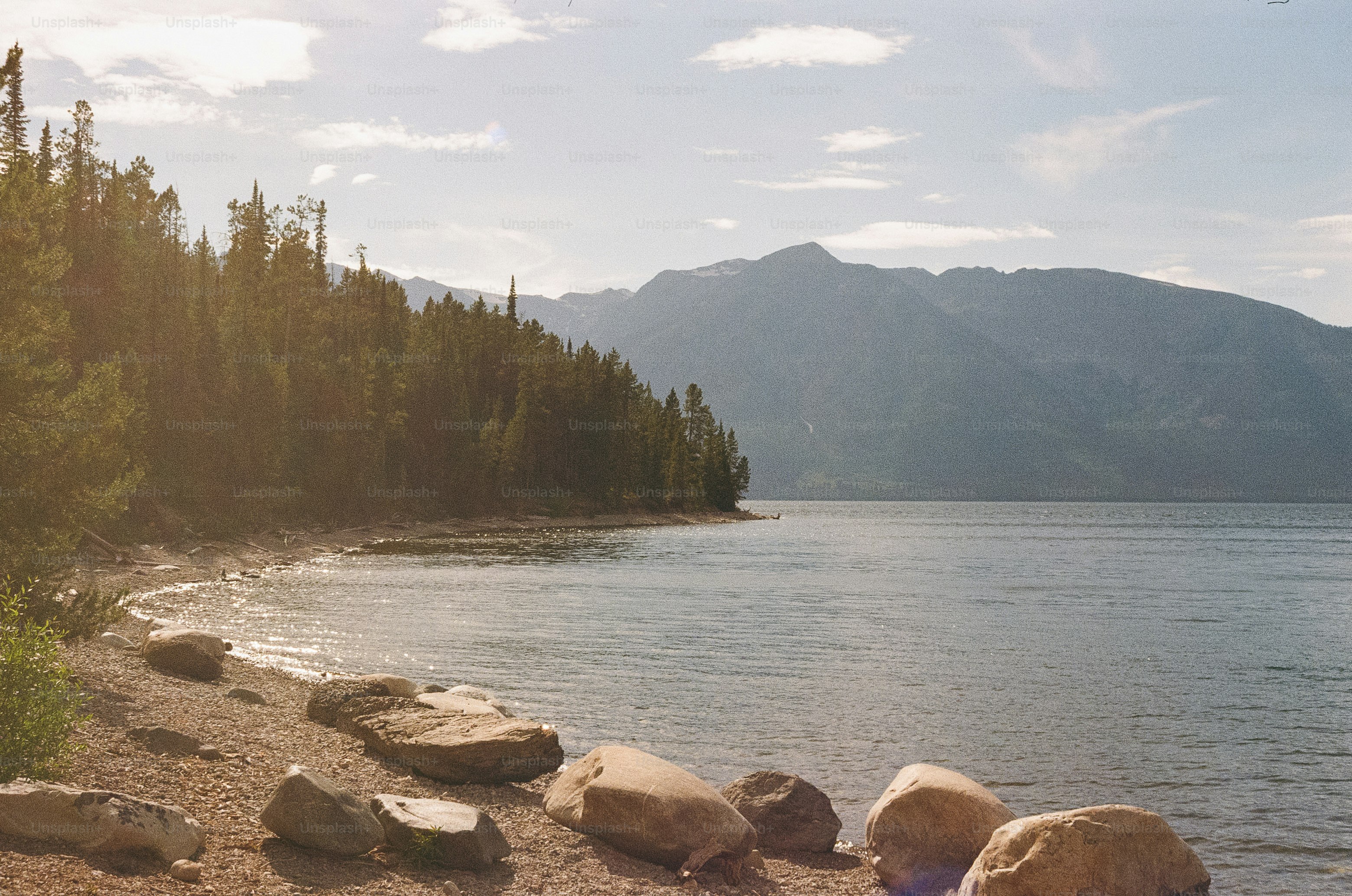 Rocky shoreline with calm lake and distant mountains