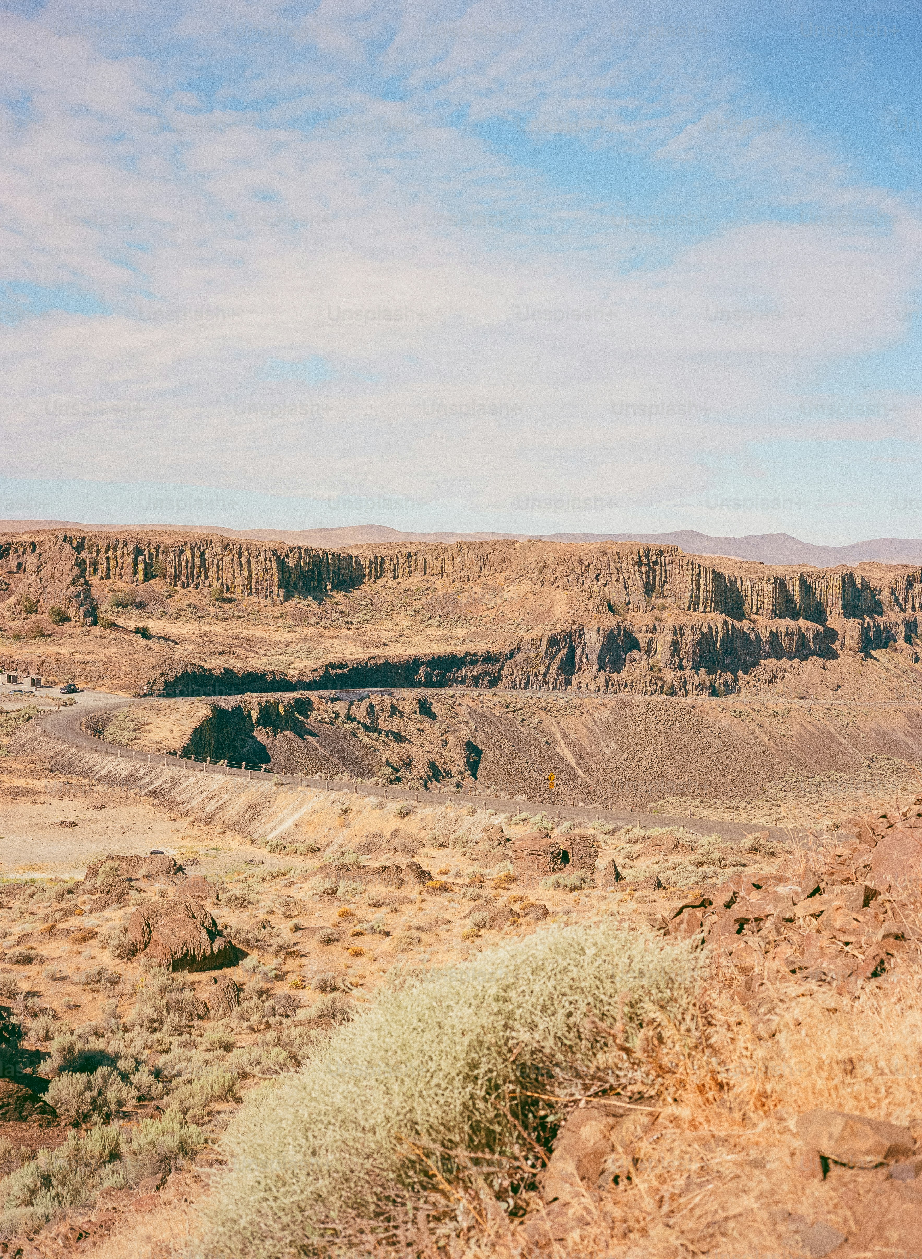 Paisagem árida com formações rochosas em camadas e vegetação esparsa
