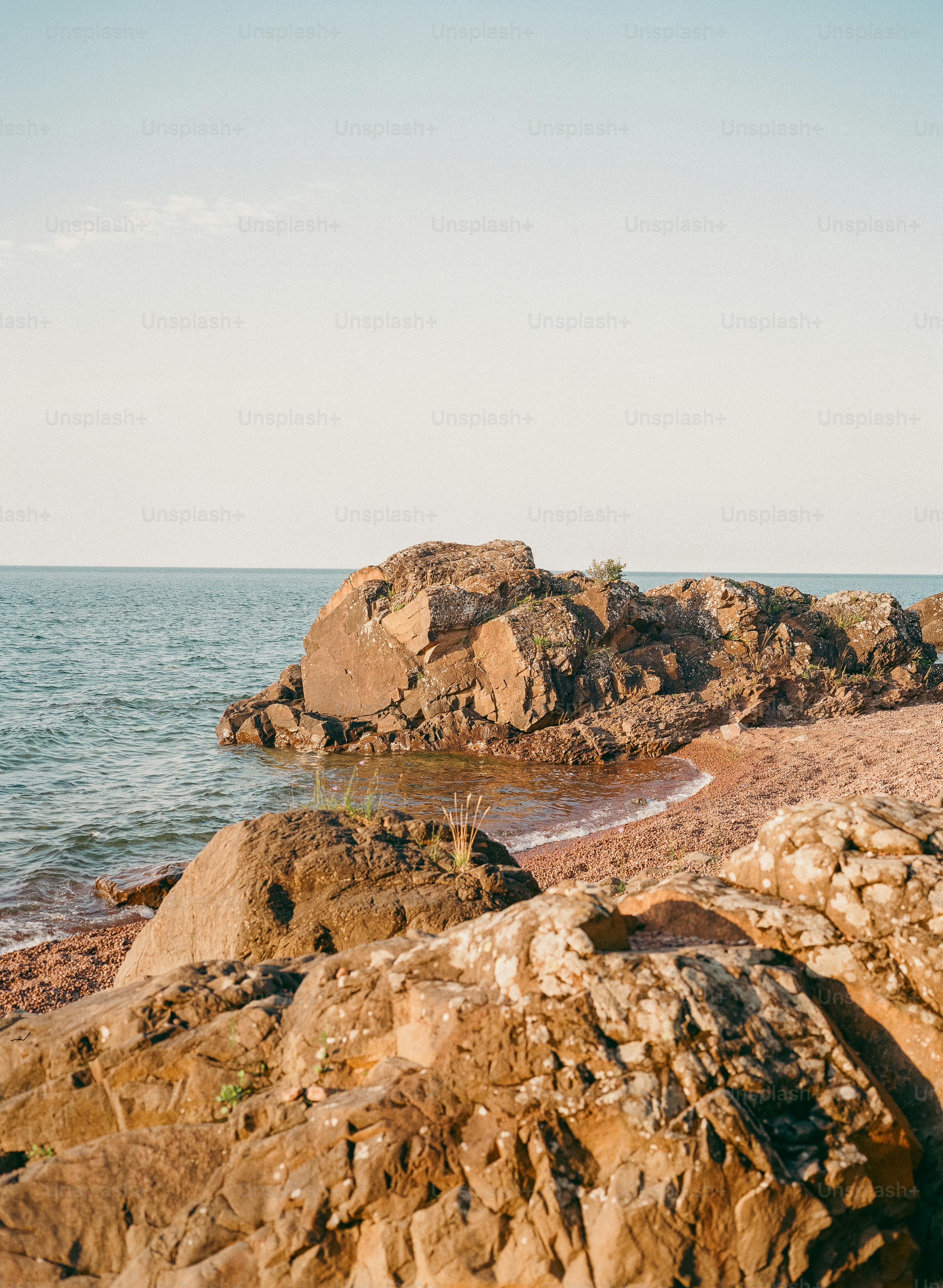 Felsige Strandpromenade mit sanften Wellen unter klarem Himmel