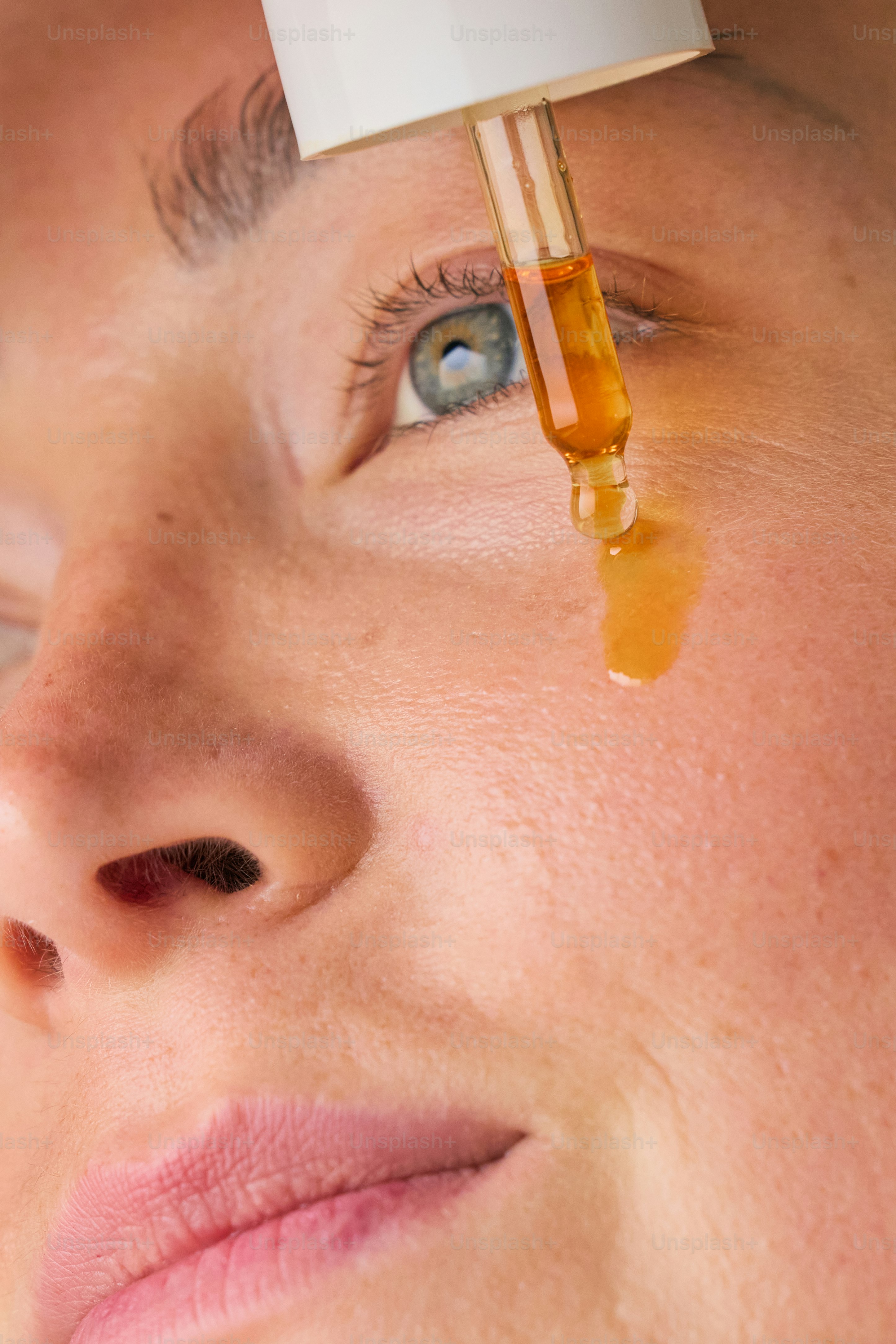 Dropper applying serum to a woman's face.