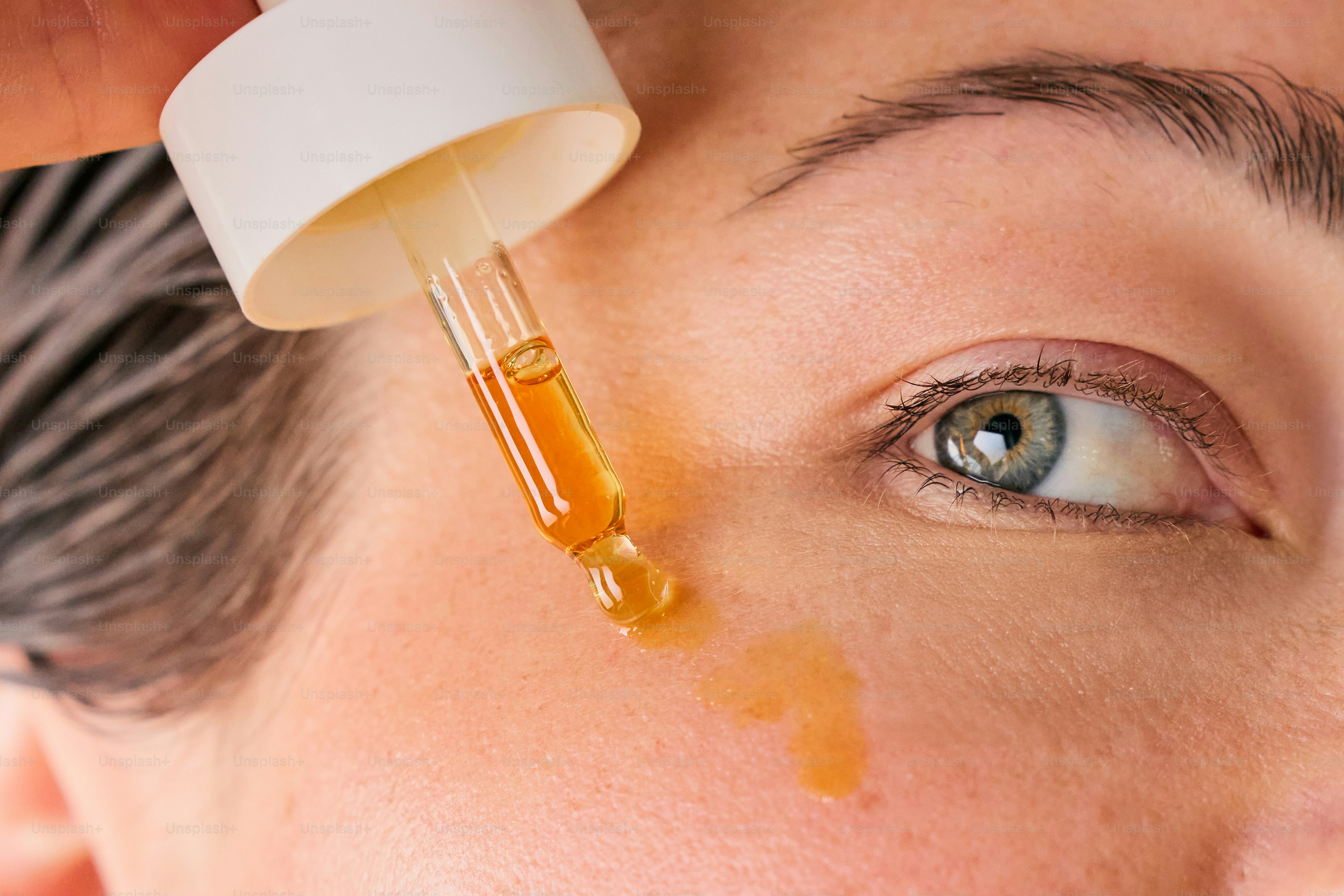 Close-up of facial serum dropper above glowing skin