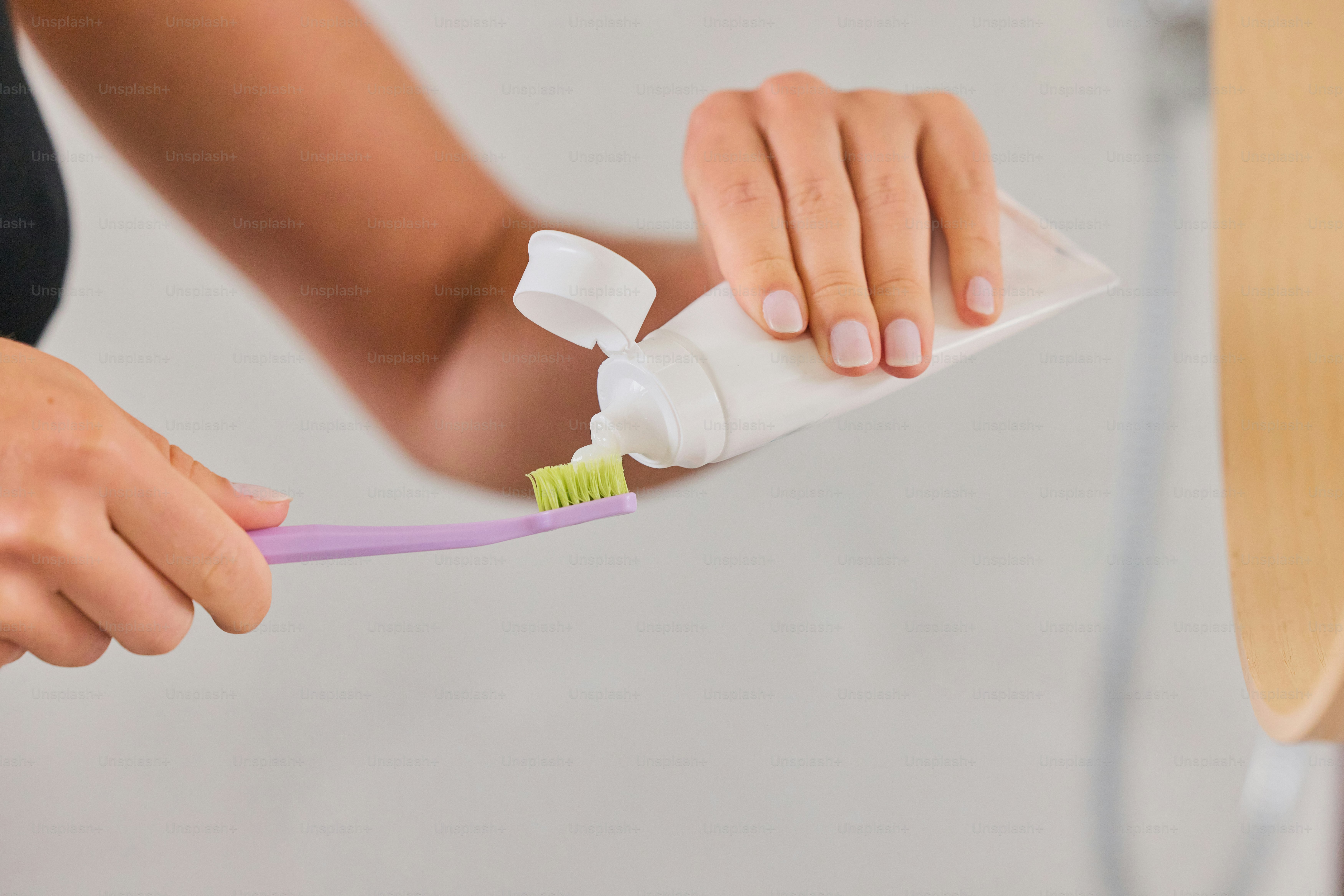 Person squeezing toothpaste onto a toothbrush