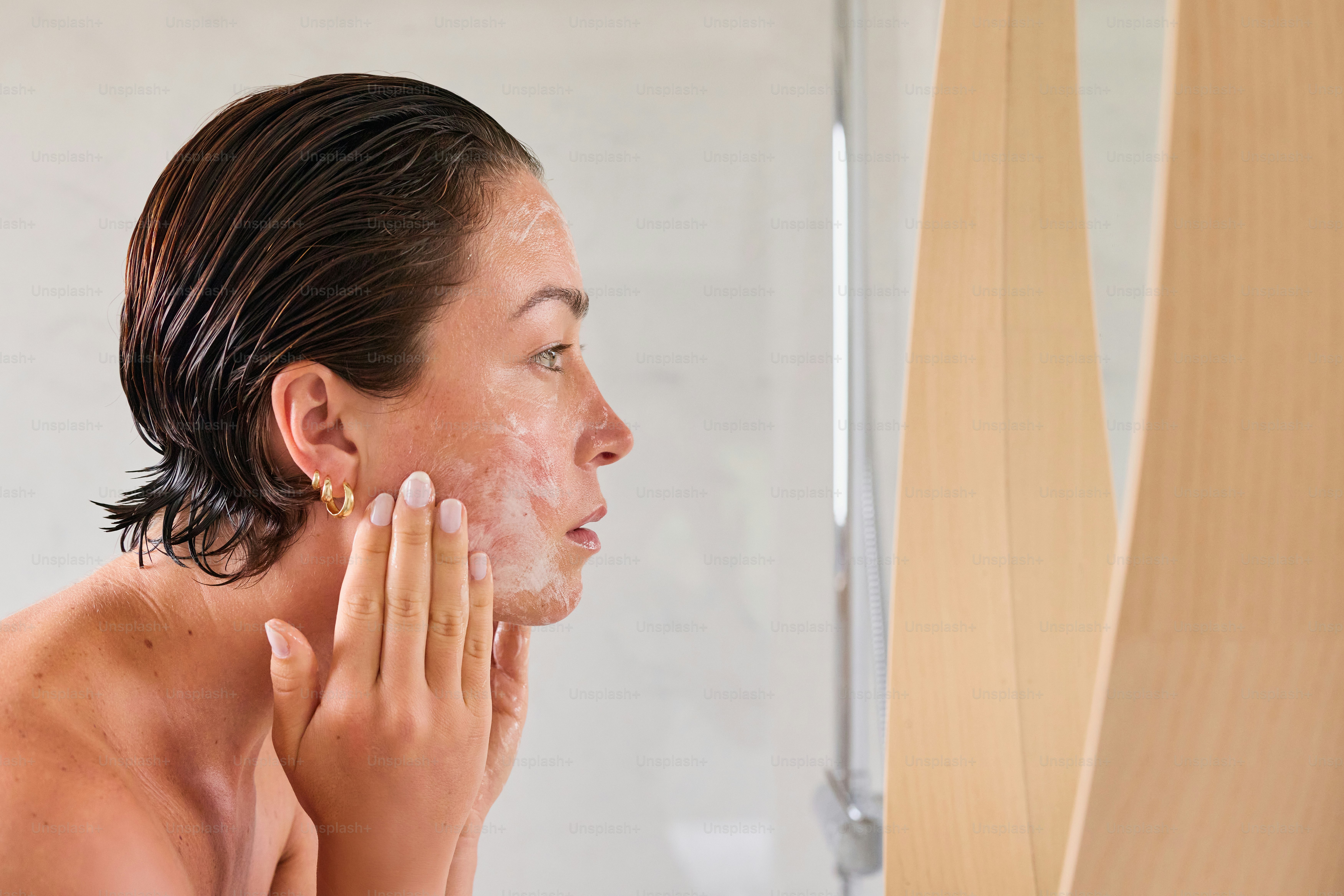 Woman cleansing her face in the mirror