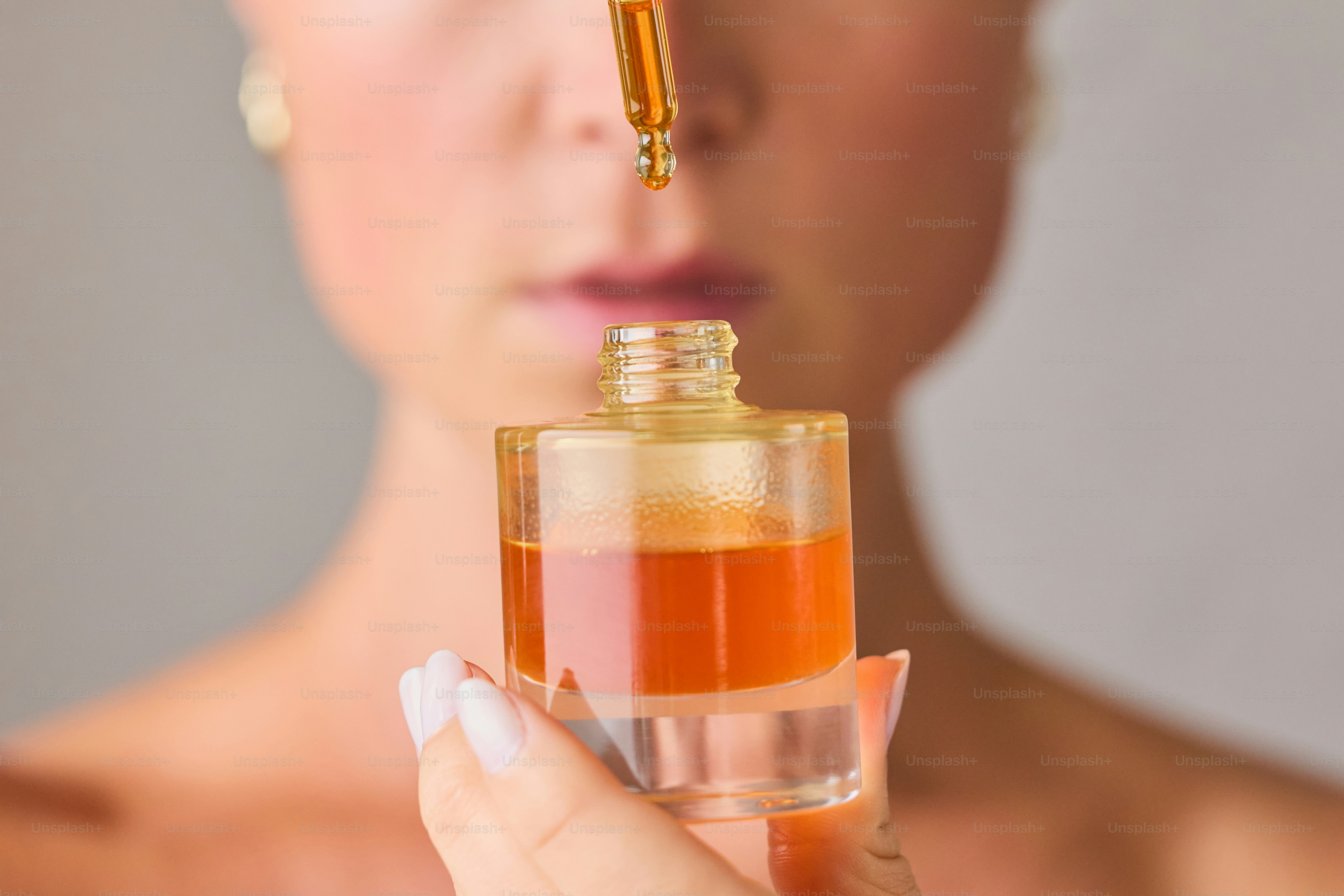 Woman applying serum from dropper to face