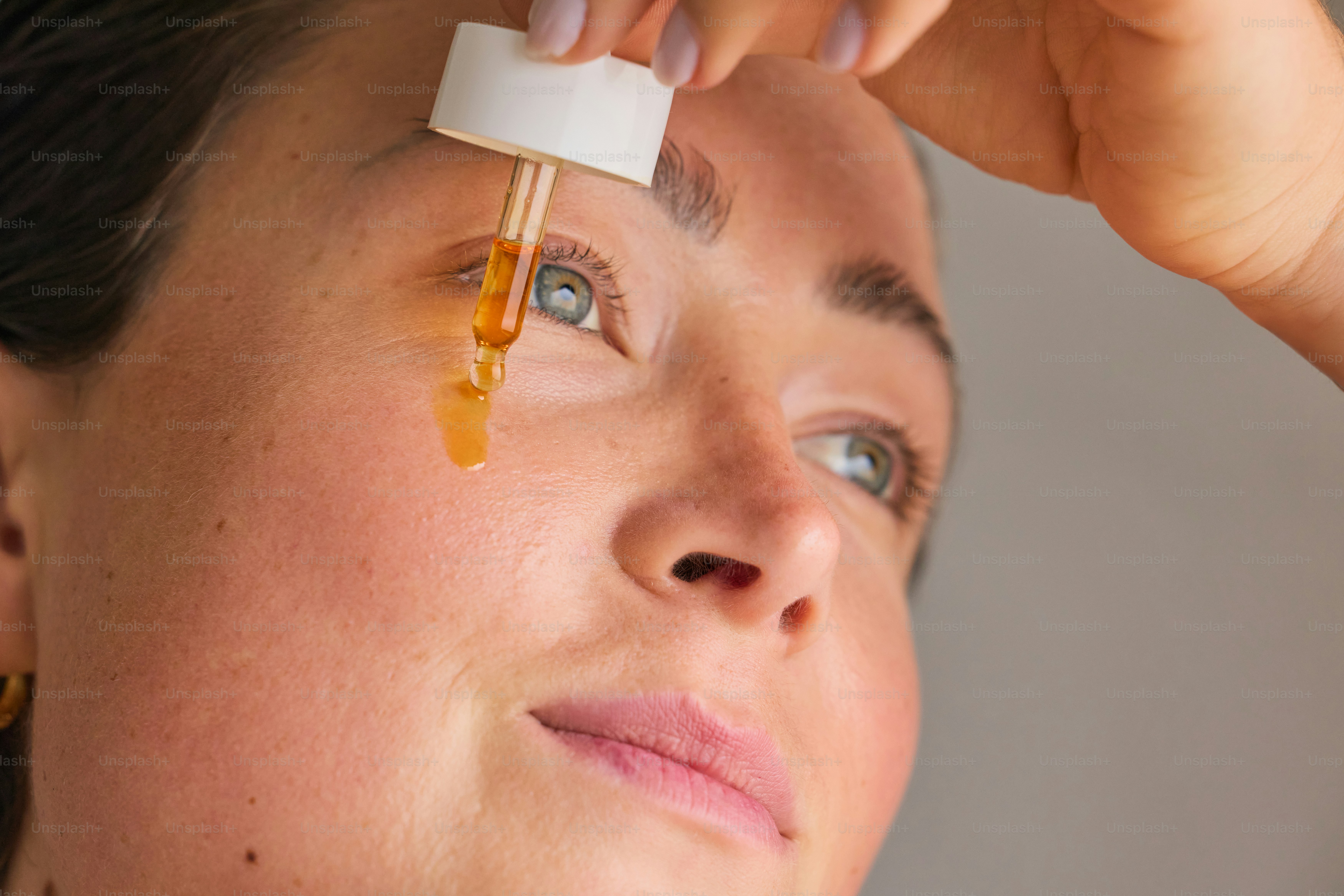 Wanita mengoleskan serum dengan penetes ke wajahnya